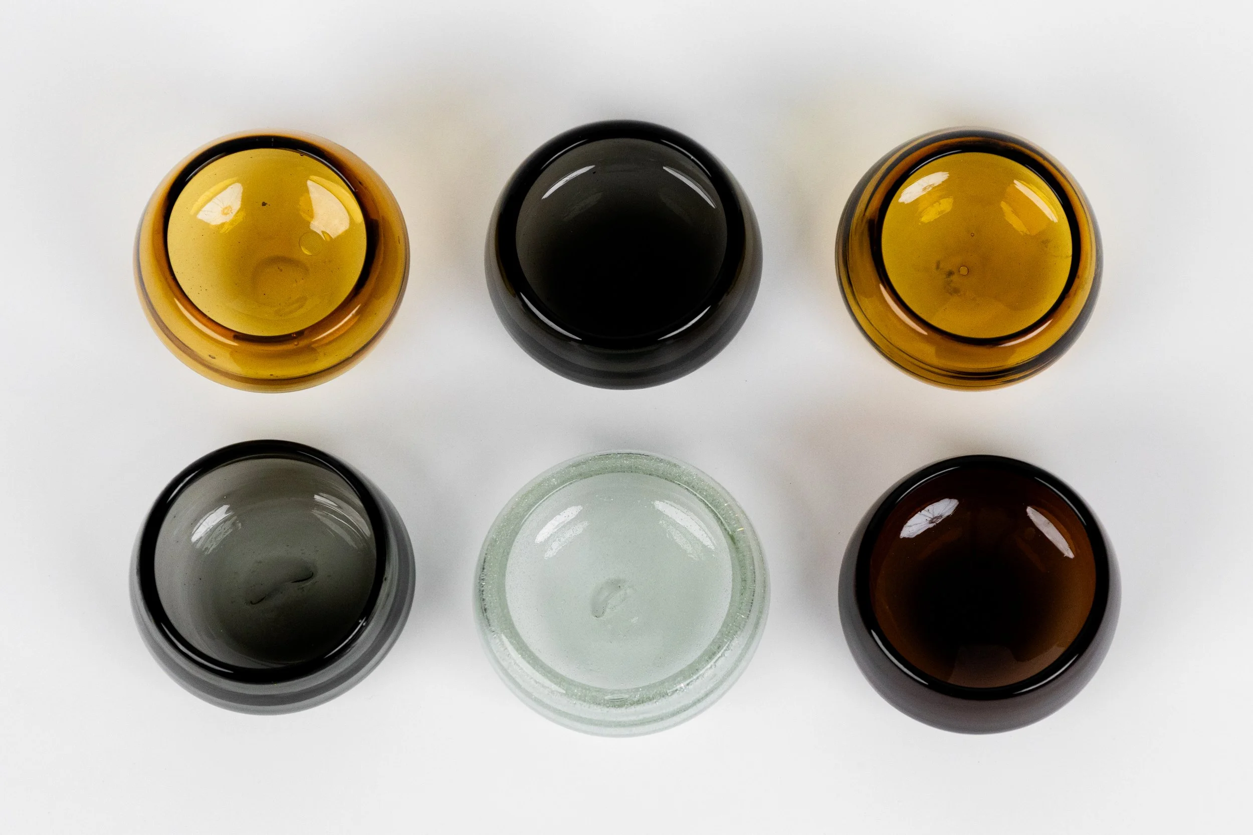 Top-down view of six small bowls on a white surface, with three filled with different liquids and three empty.