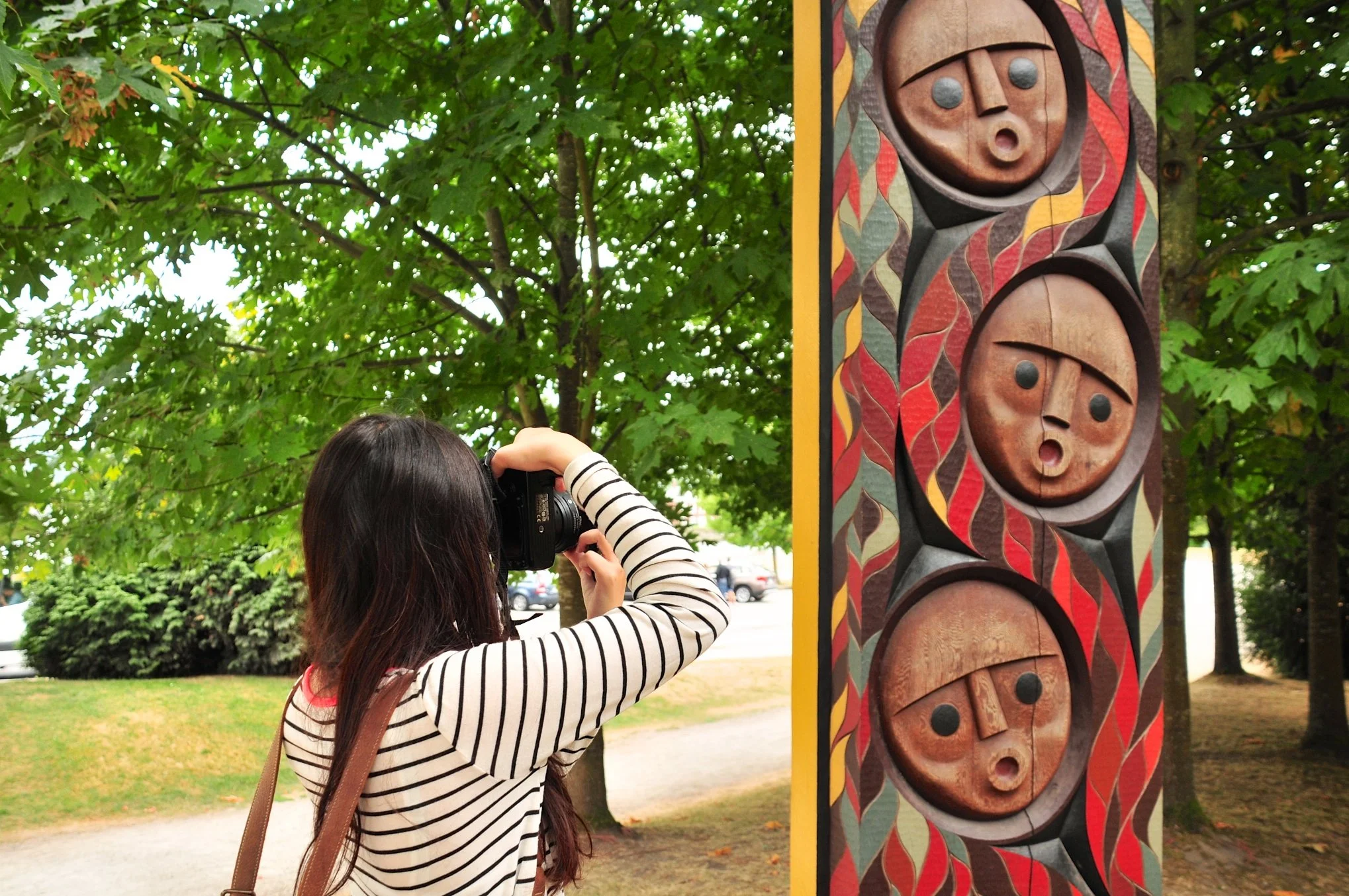 Student aiming camera at colourful totem pole during Vancouver photo walk