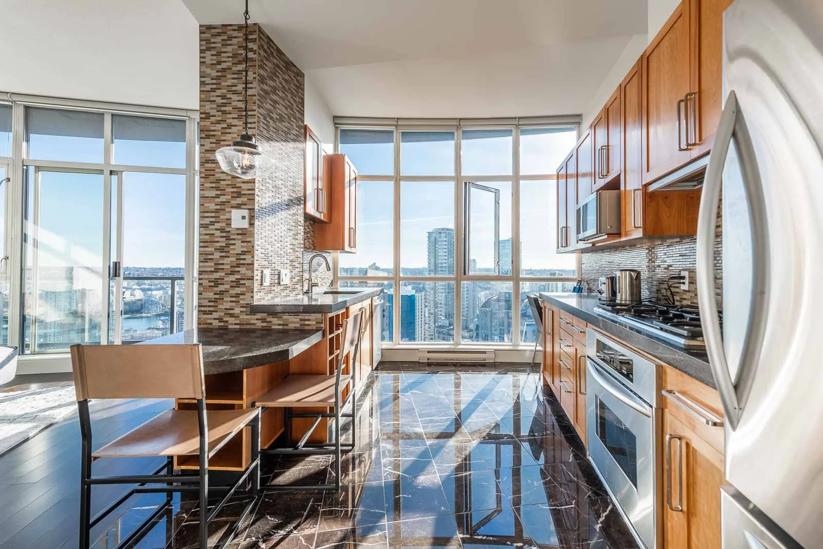 Modern condo kitchen with wood cabinetry and city views, interior photography Vancouver