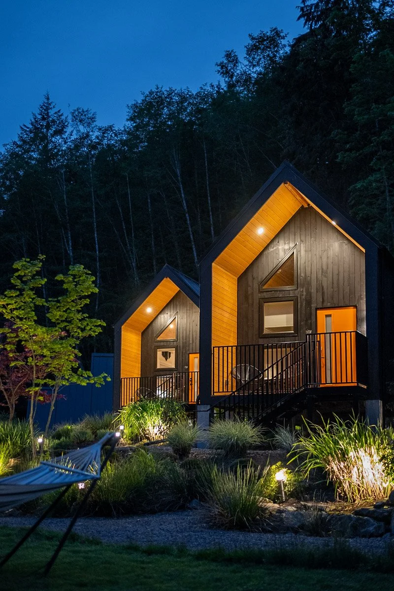 Retreat cabins at Nectar Yoga Retreat lit at night in forest, architectural photography