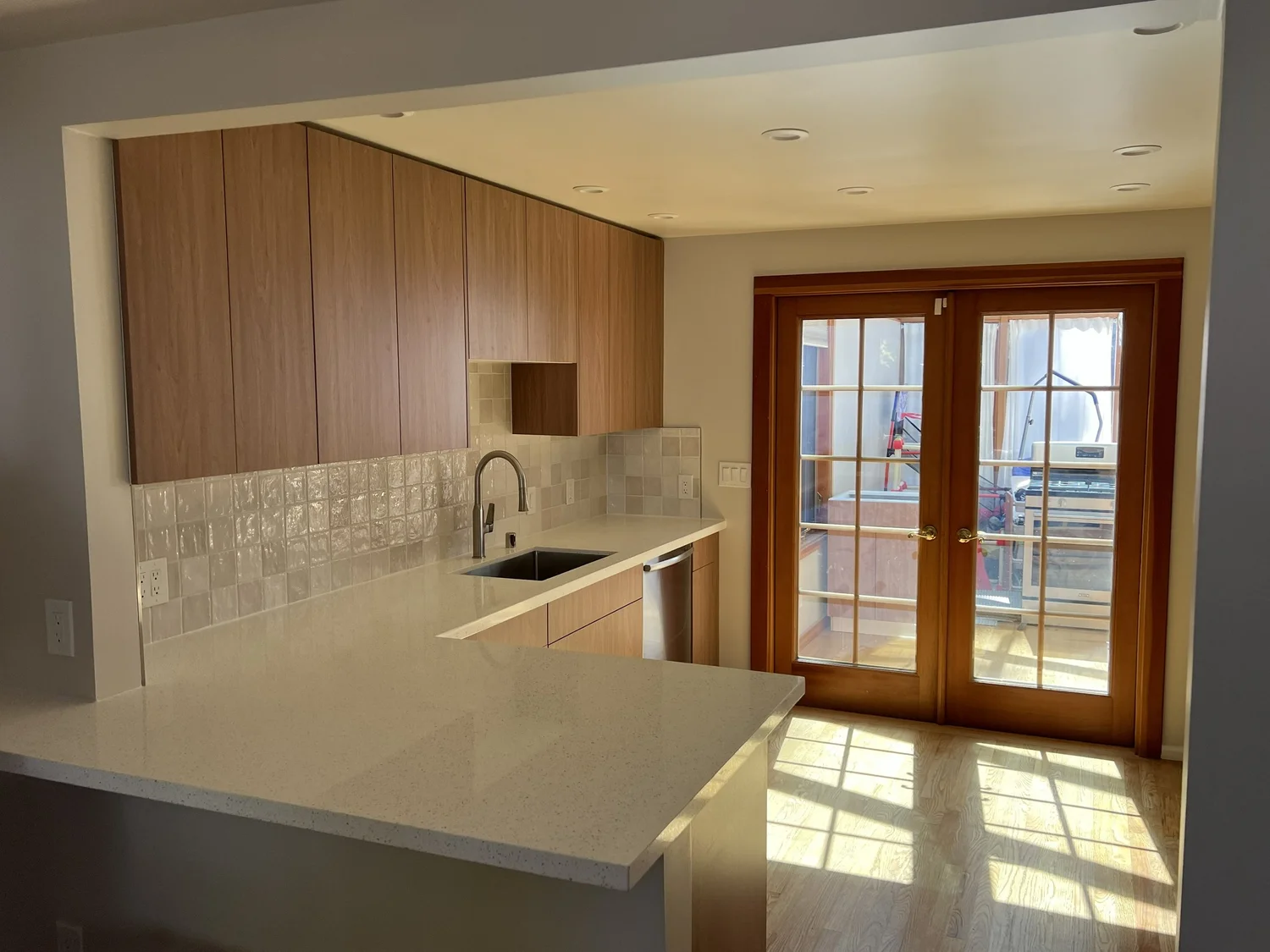 Remodeled kitchen with wood cabinetry, quartz countertops and French doors in Seattle