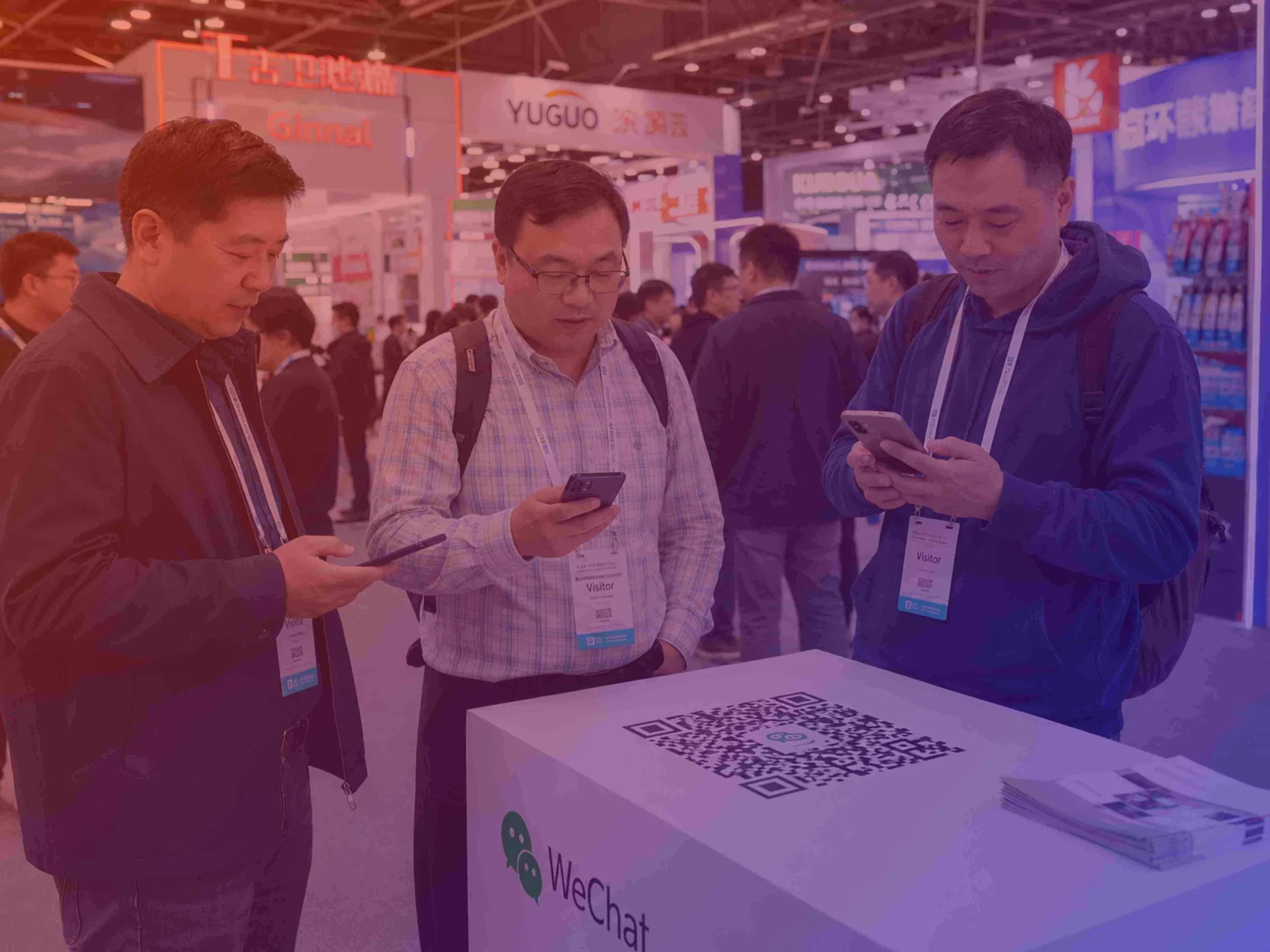 Group of Asian trade show visitors scanning WeChat QR code.