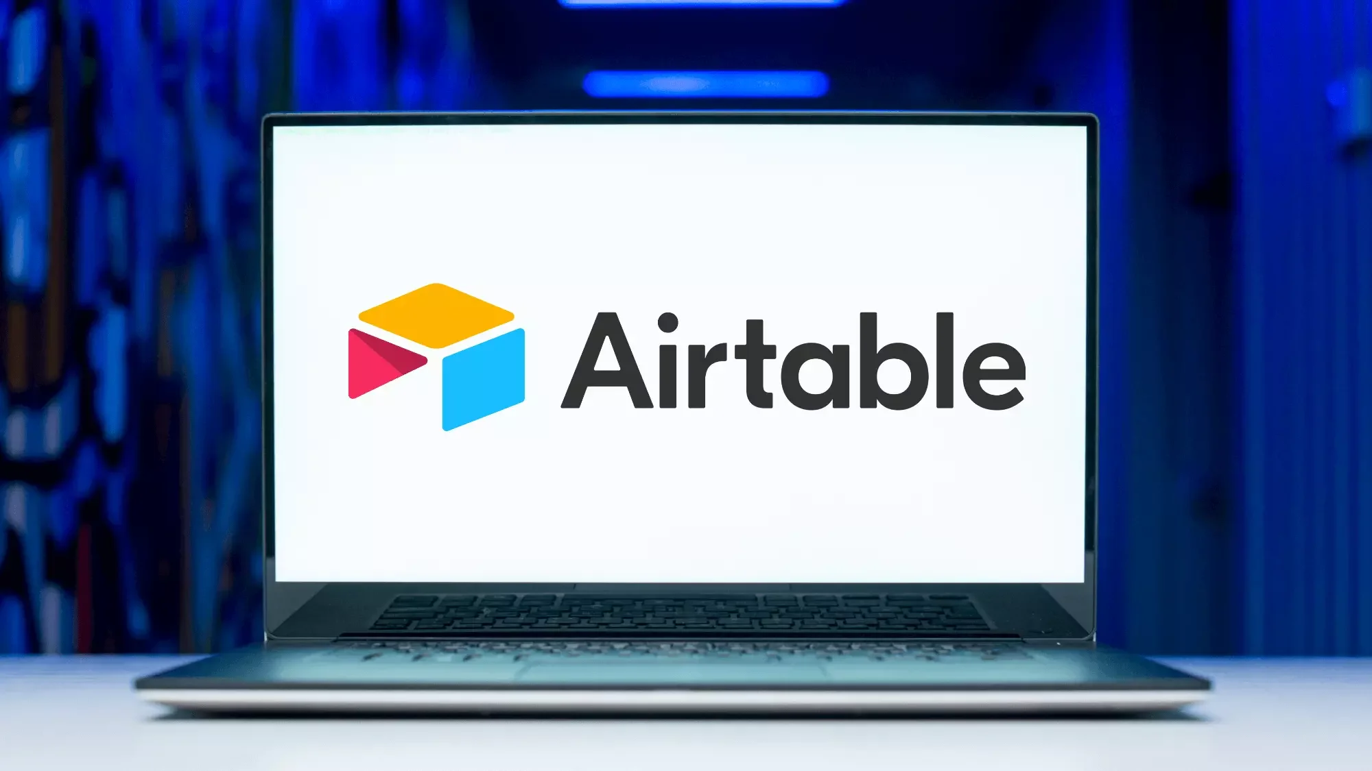 A laptop on a desk displaying the Airtable logo on its screen.