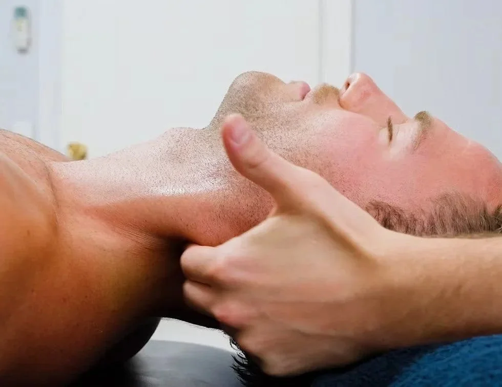Fitness instructor assisting a woman with resistance band exercises in a gym, with a stability ball in the background.