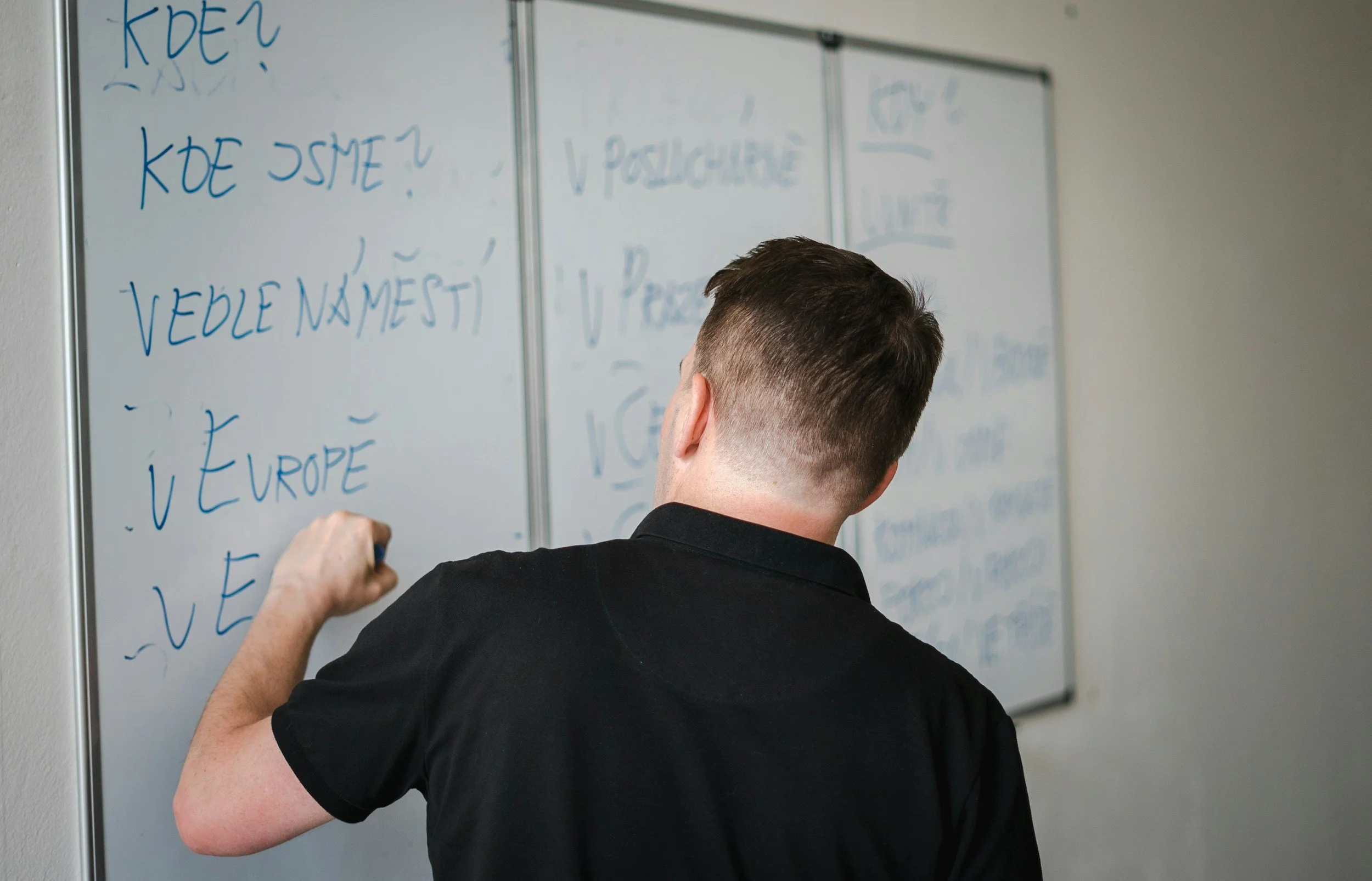 A person writing on a whiteboard in a classroom or office setting.