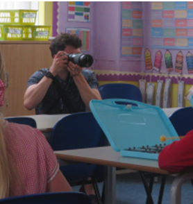 Person taking a photo with a camera in a colorful classroom.
