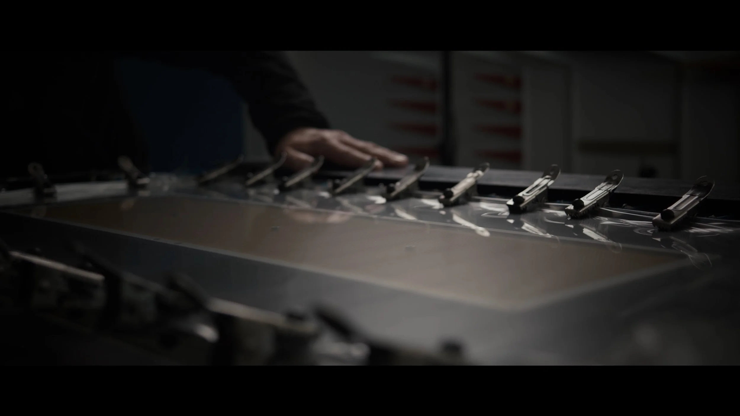 Nahaufnahme einer Person, die einen industriellen Schneide- oder Zuschnittmaschinen bedient, während die Maschine in Betrieb ist.