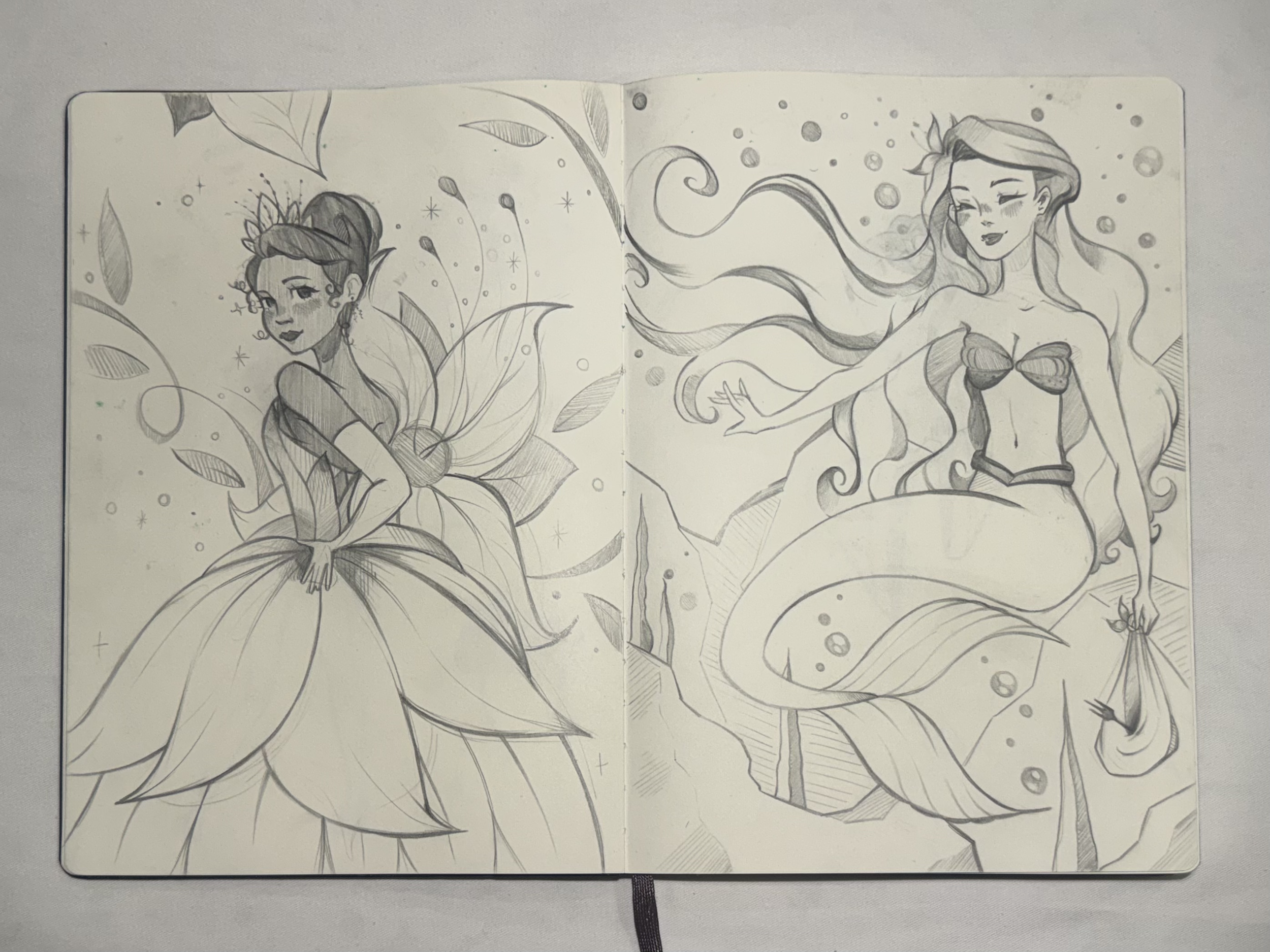 A black and white sketch of two women with long flowing hair, surrounded by leaves, flowers, and swirling patterns.