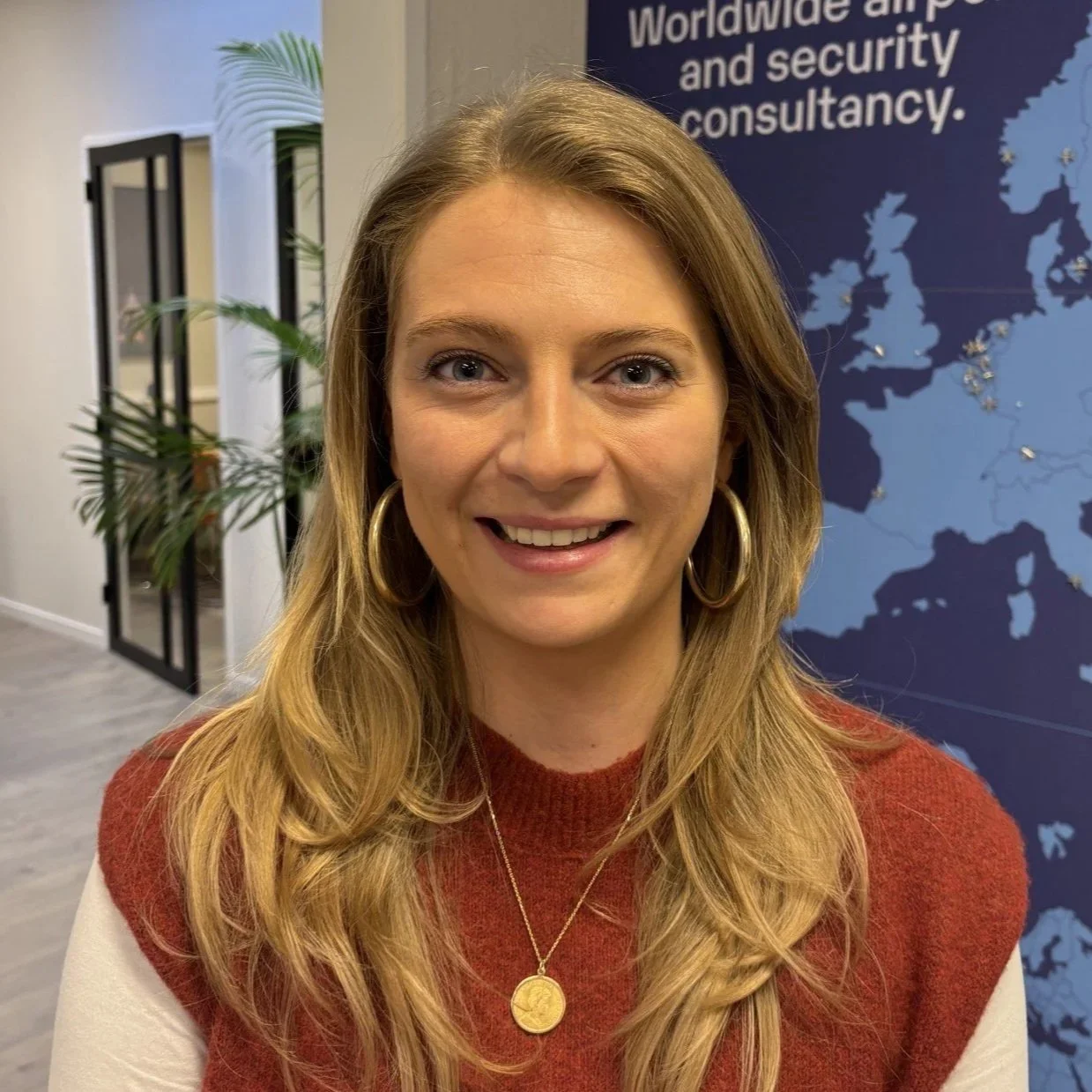Blond woman in an office with a gold necklace