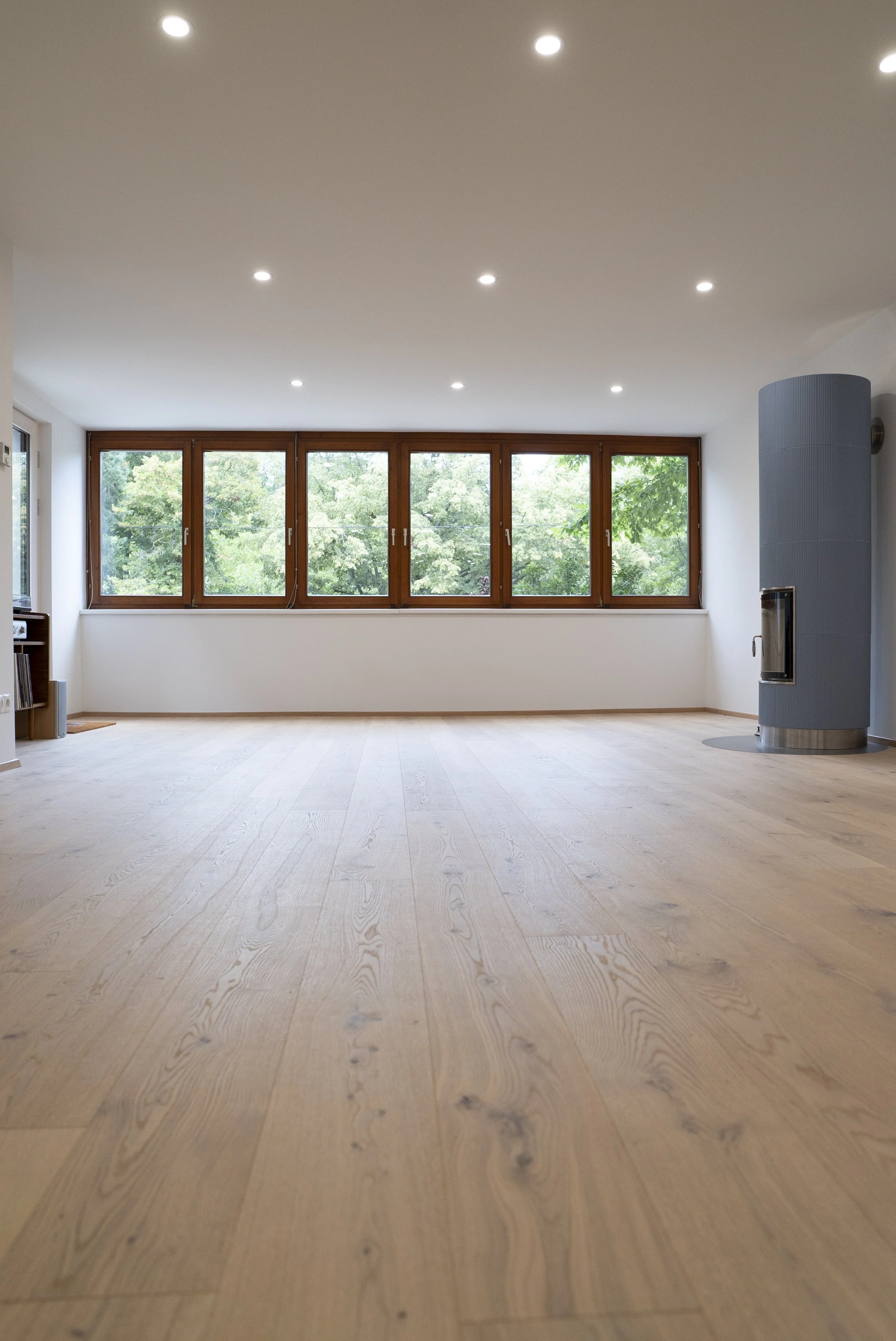 Yogastudio Krottenbachstraße 1190 Wien: Loftartiges Yogastudio mit großen Fenstern, Holzfußboden und moderner Kaminecke.