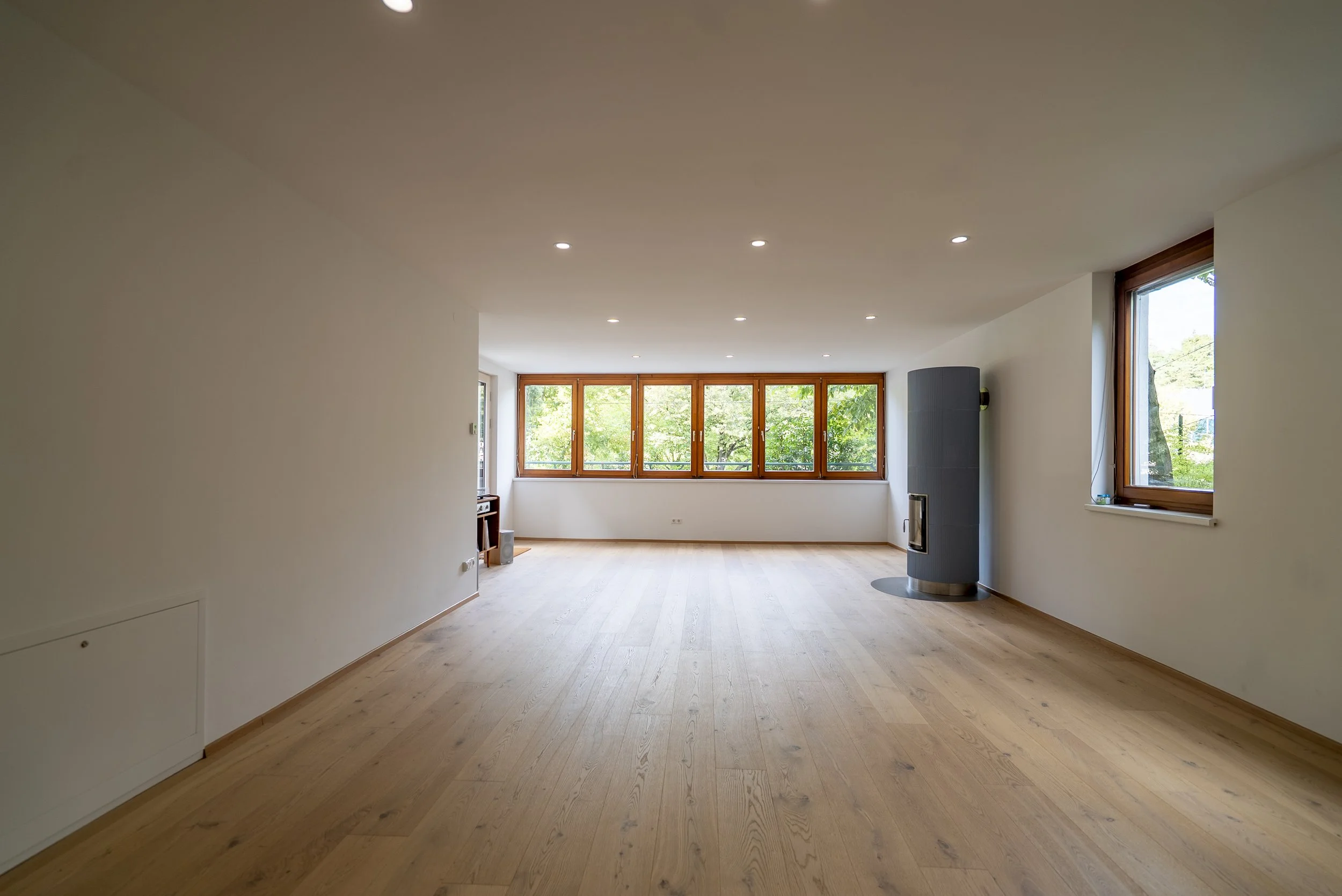 Yogastudio mit vielen Fenstern, Holzboden und Kamin.