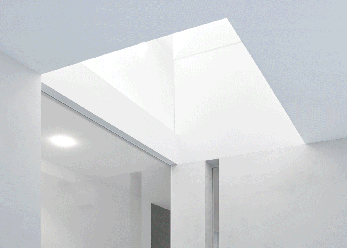 Ein modernes, hell erleuchtetes Innenraum mit weißem Deckenpaneel und großen Fensterflächen, minimalistische Architektur.