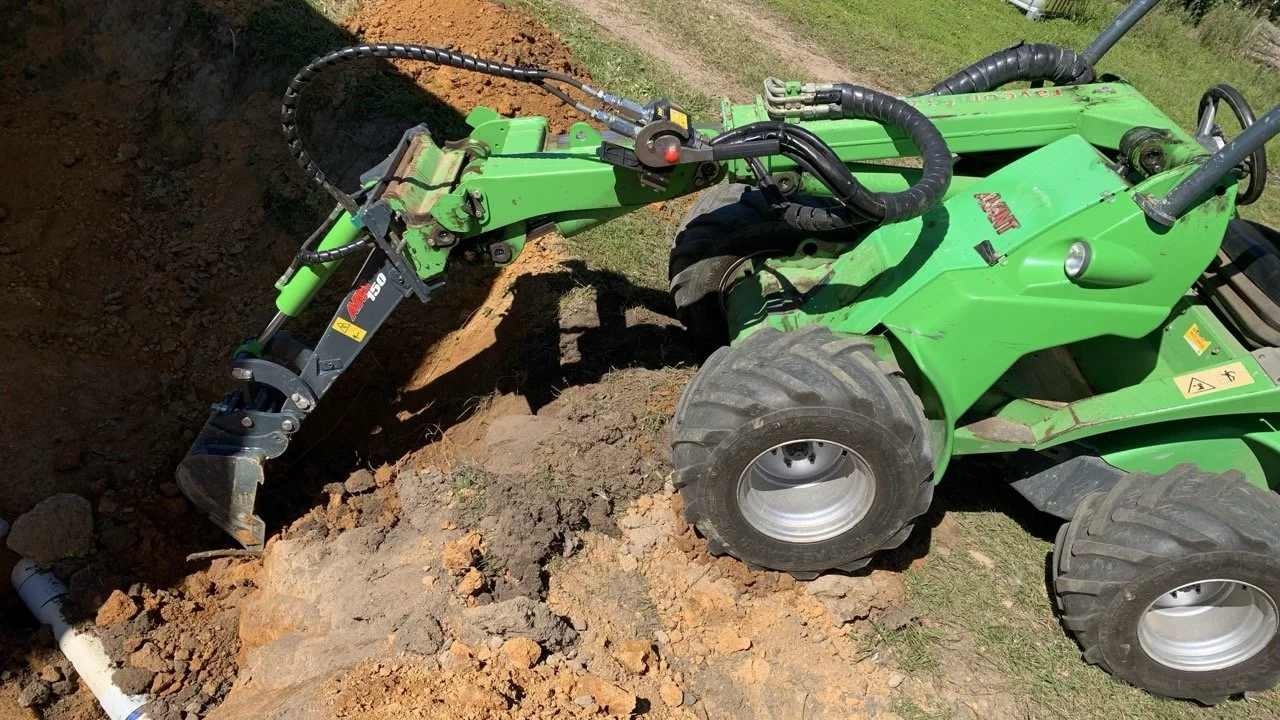 Green Avant loader articulated machine digging out soil with the digger attachment