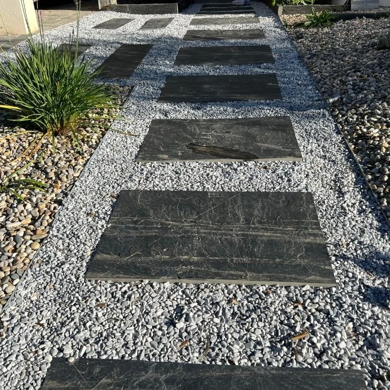 Stepping stones along a gravel and pebble pathway, surrounded by plants in a beautifully designed garden walkway