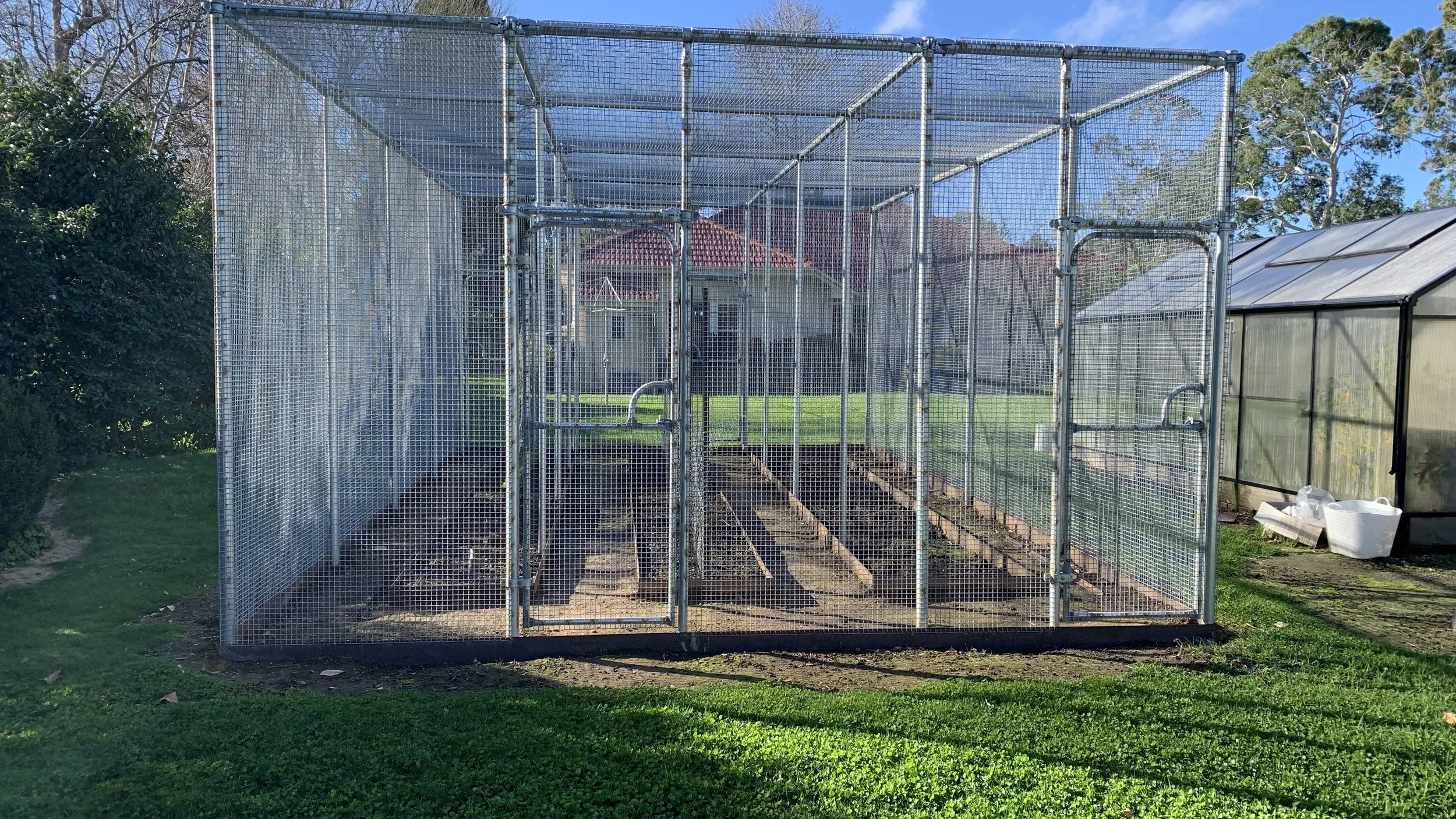 Close-up of a steel mesh chicken coop enclosure with a detailed view of the gates and steel edging gardens