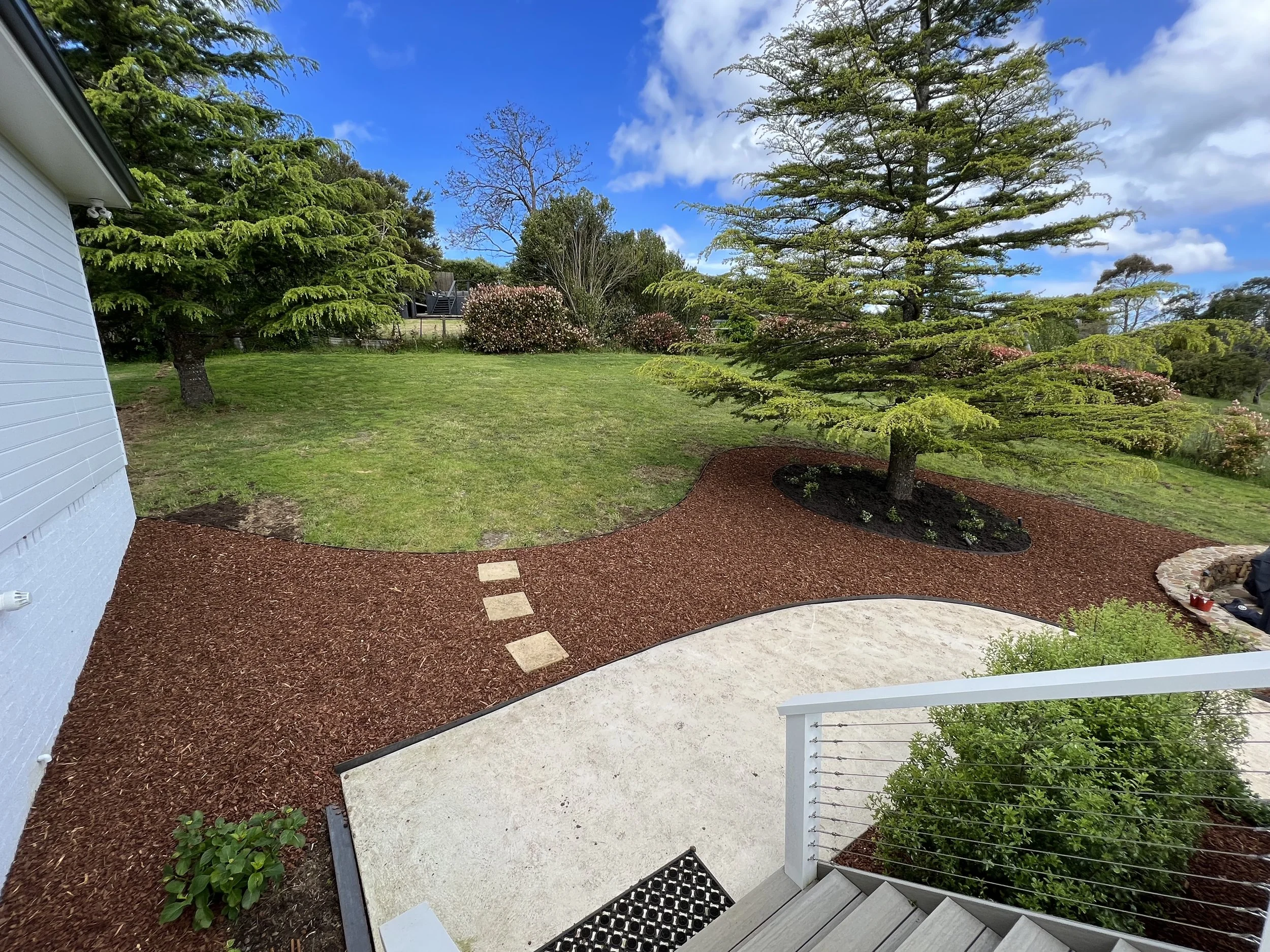 Landscaped garden with steel edging, mulched garden beds, and decorative stone path leading through a well-maintained outdoor space.