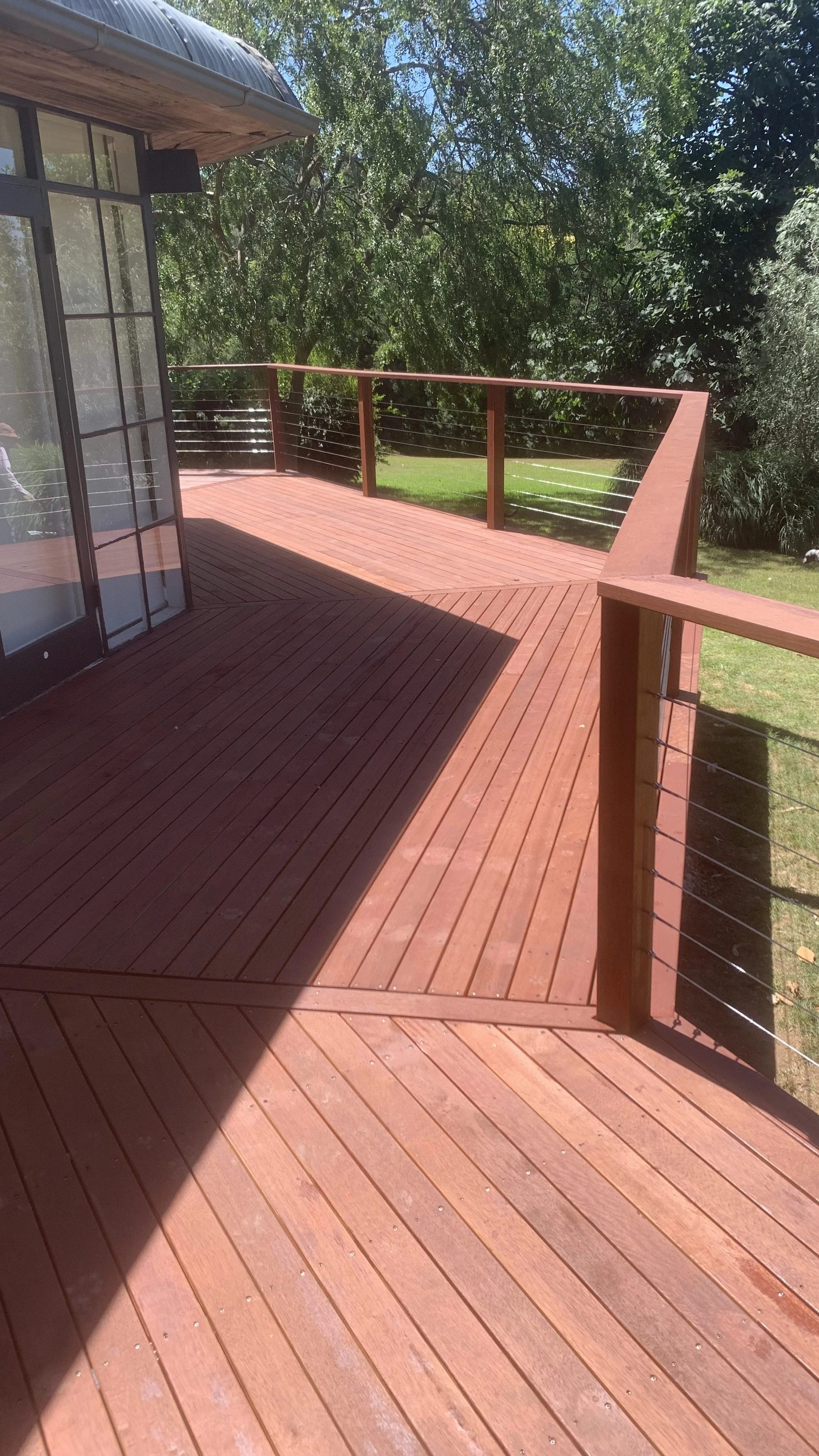 Wooden deck flooring with sleek horizontal boards and a view of the surrounding green landscape.