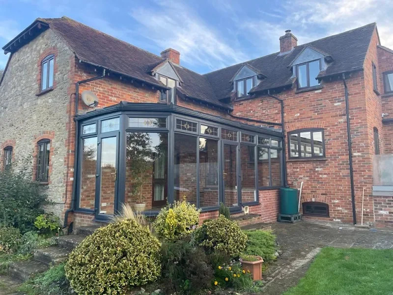 Brick house with a glass conservatory and garden in front.