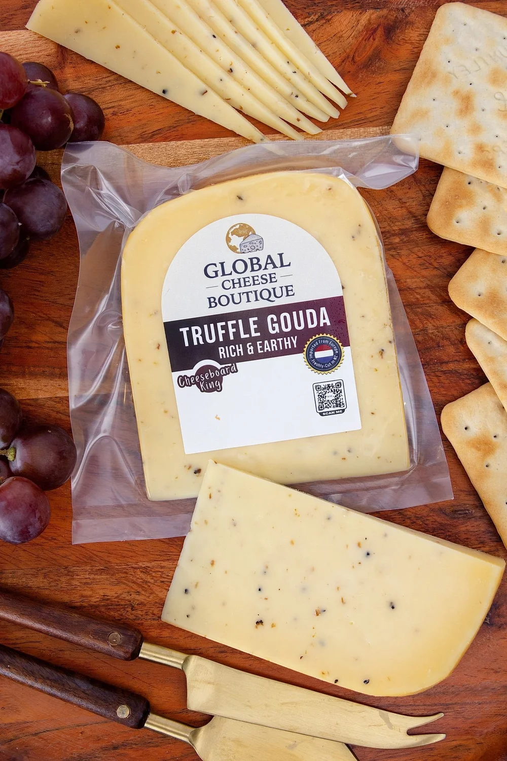 Truffle Gouda pack, wedge and slices with grapes and crackers on a wooden board