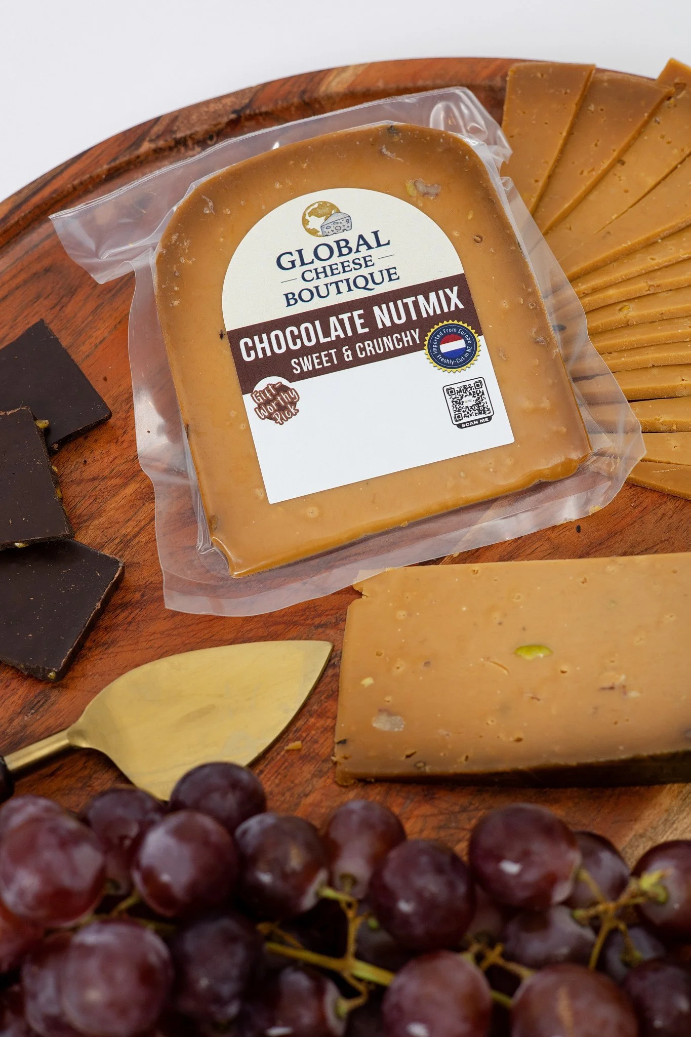 Chocolate Nutmix Gouda 180 g, sealed pack and slices on a board with grapes