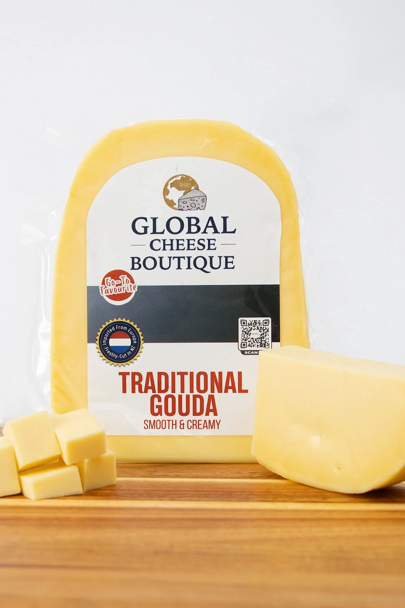 Traditional Gouda, sealed pack with a wedge and cheese cubes on a wooden board