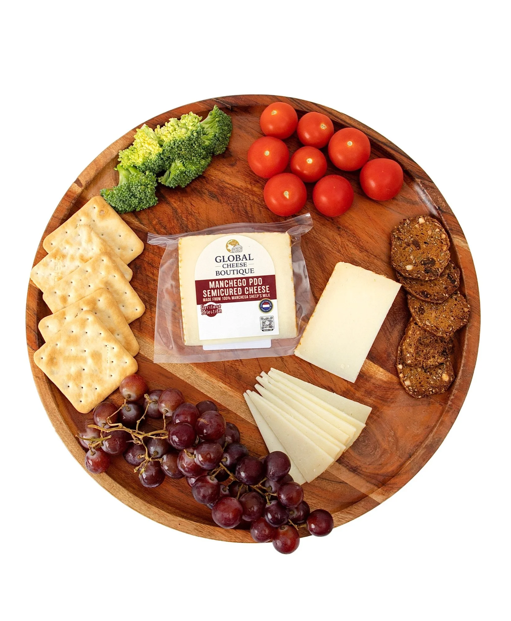Spanish Manchego 140 g on a round board with crackers, grapes, cherry tomatoes and slices