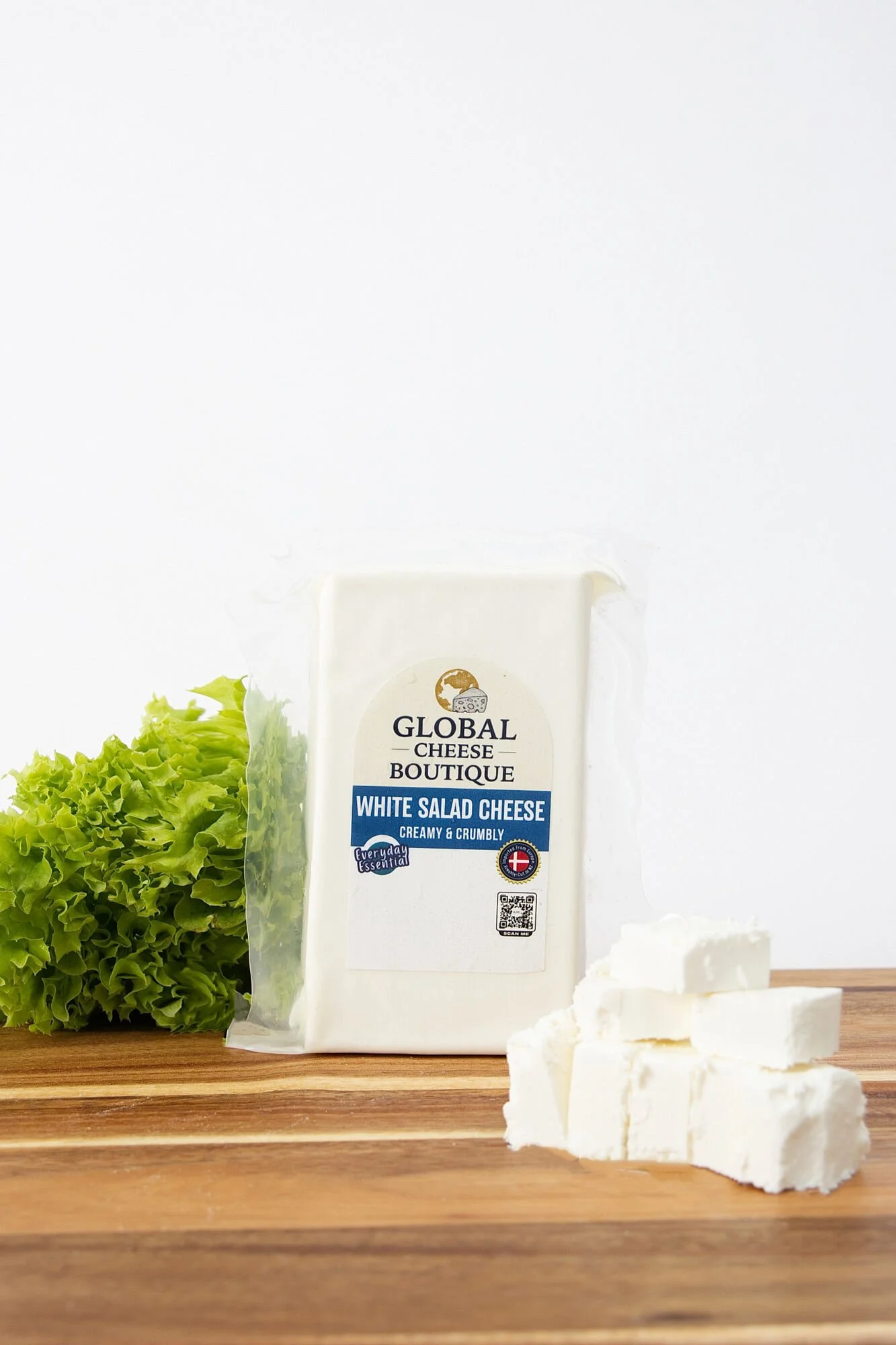 White Salad Cheese 230 g with lettuce and cheese cubes on a wooden board