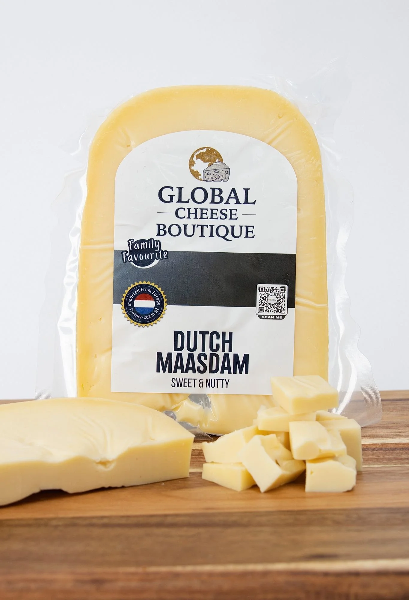 Dutch Maasdam, sealed pack with a cut cheese piece and cubes on a wooden board