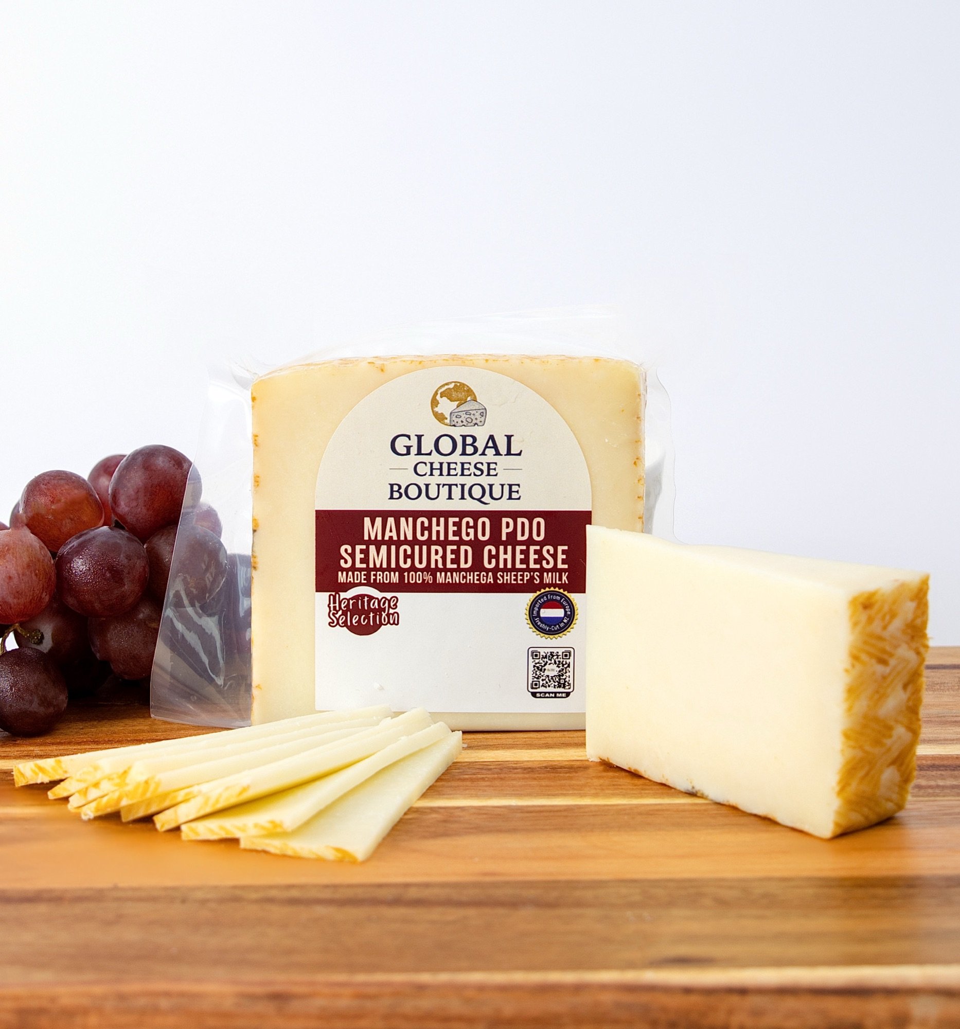 Spanish Manchego 140 g with red grapes, thin slices and a wedge on a wooden board