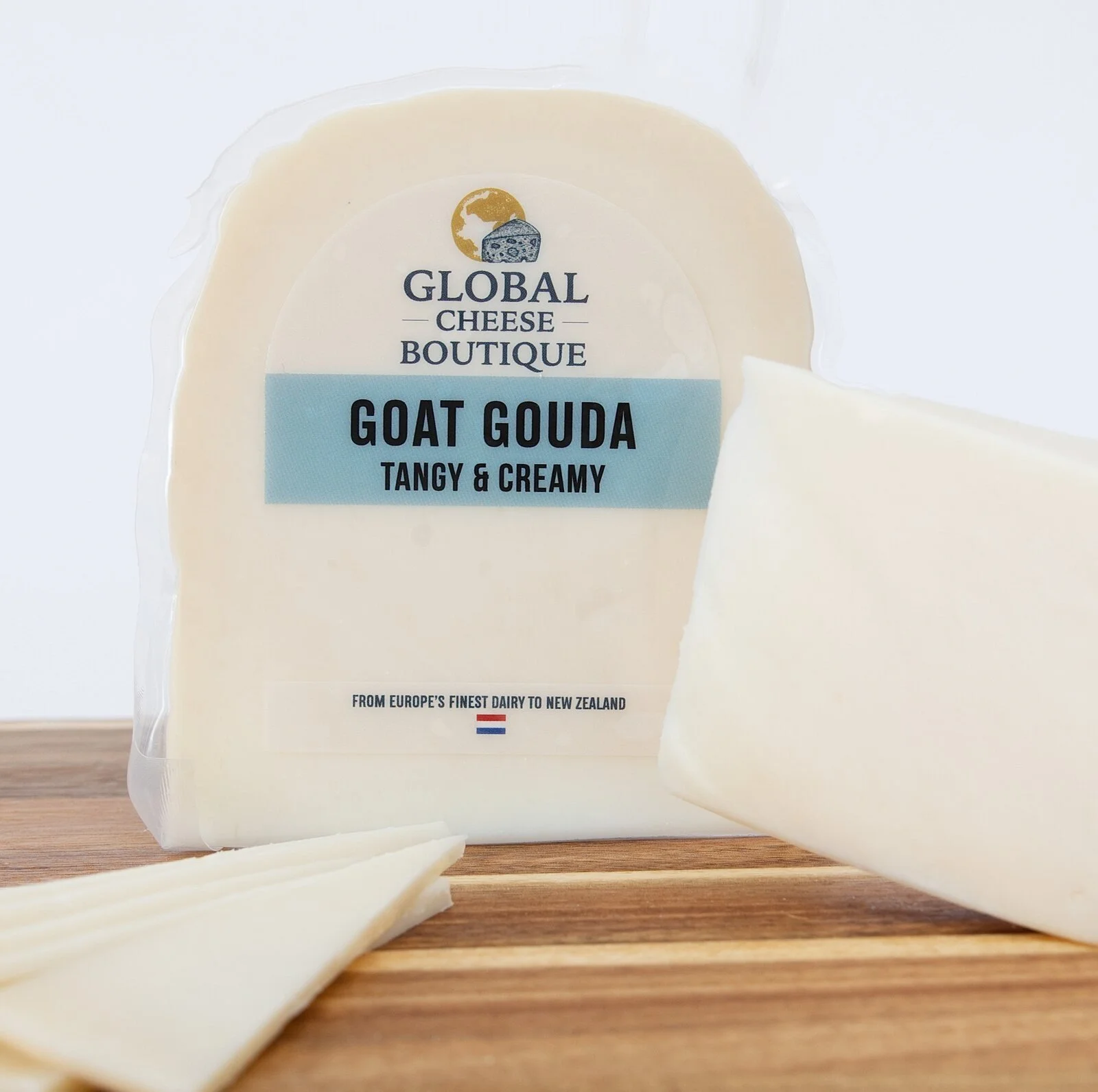 Goat Gouda pack standing on a wooden board beside a wedge and slices.