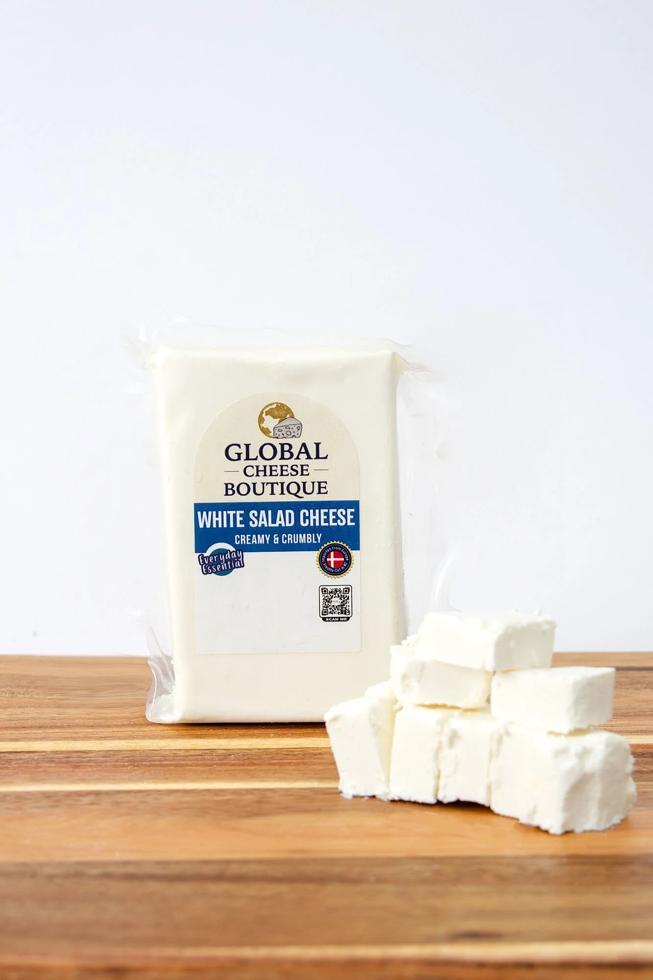 White Salad Cheese 230 g pack on a wooden board with a stack of cheese cubes