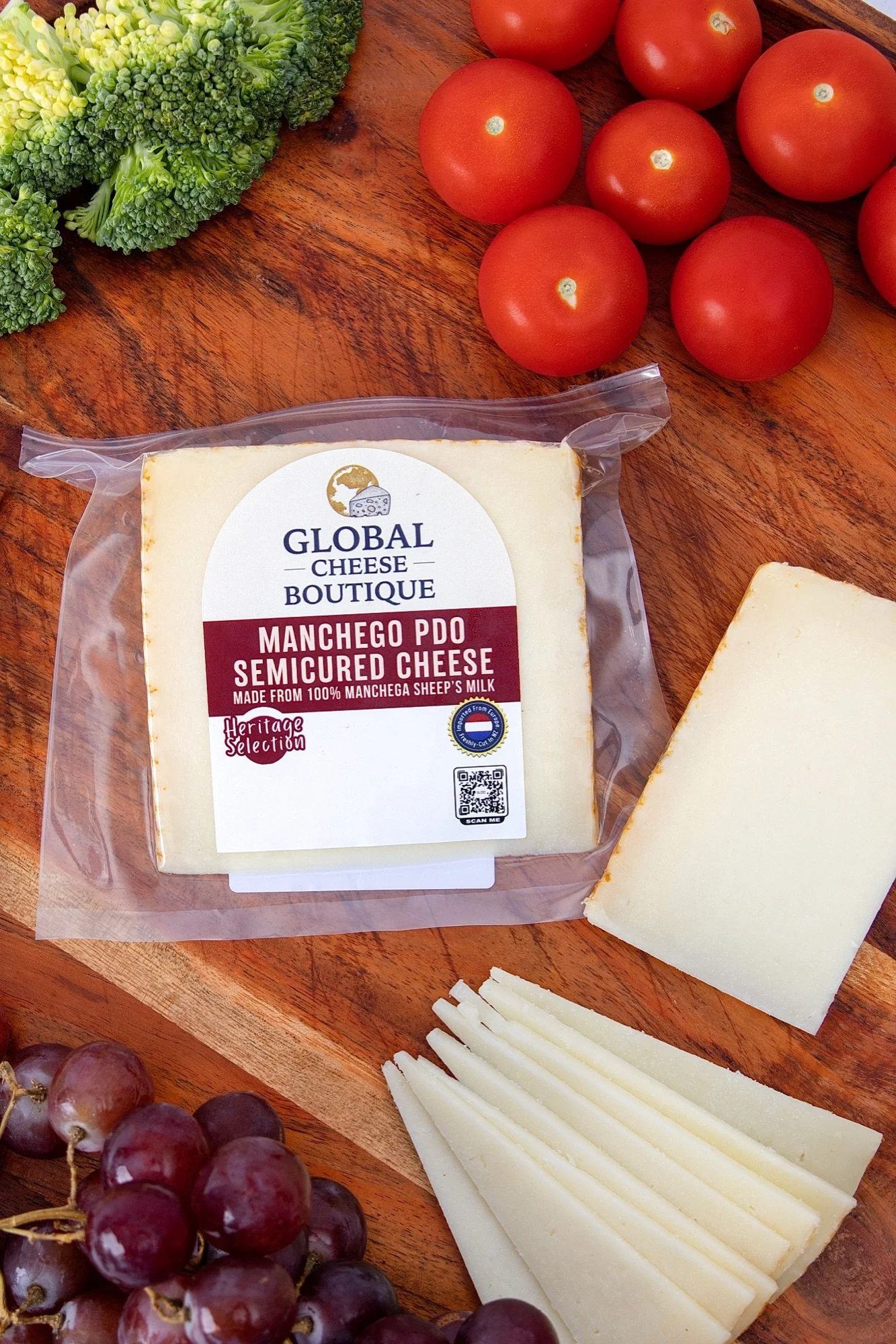 Overhead view of Spanish Manchego 140 g with cherry tomatoes, broccoli, grapes and slices