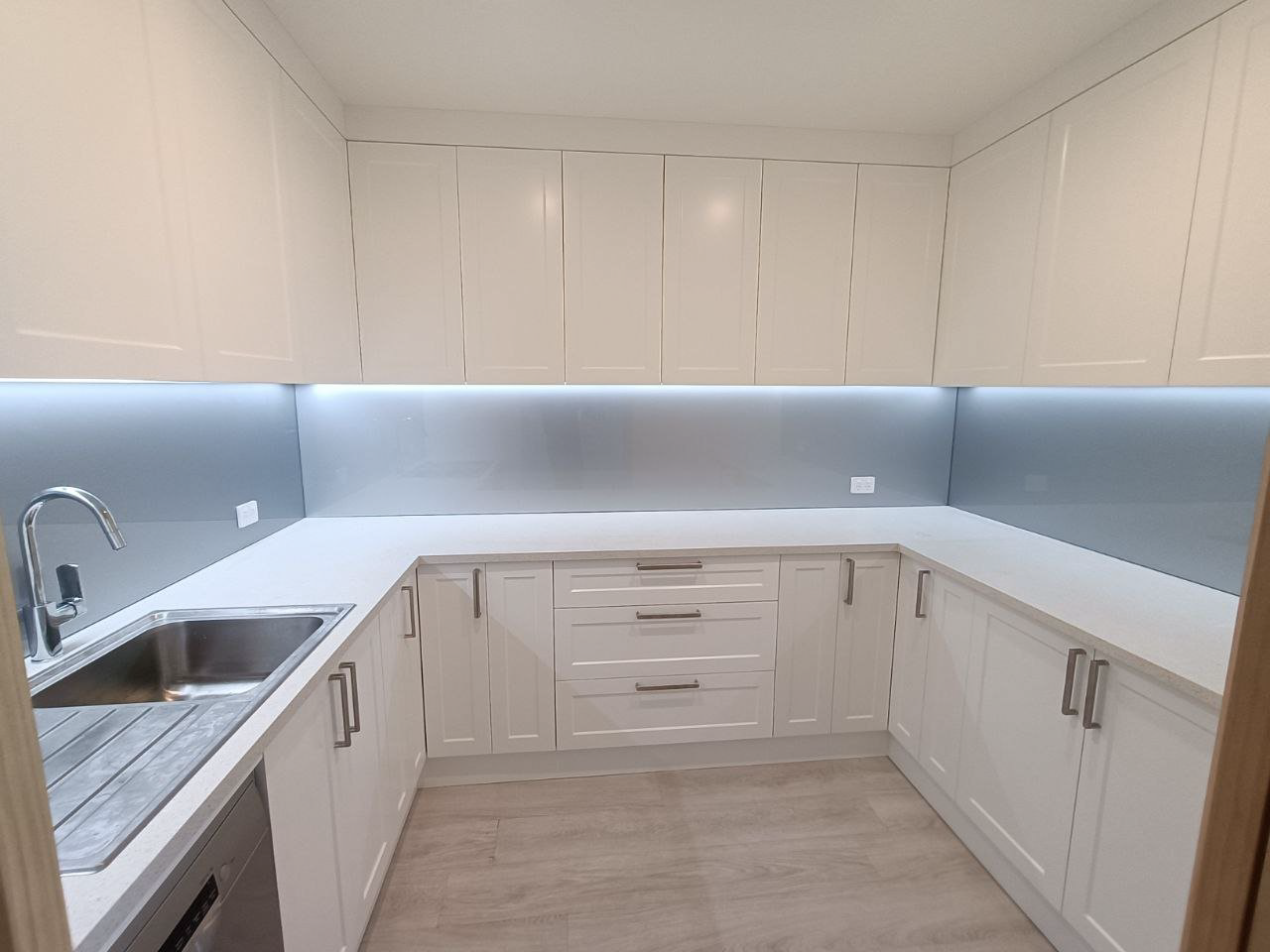 Custom glass splashback installation in a modern home kitchen.