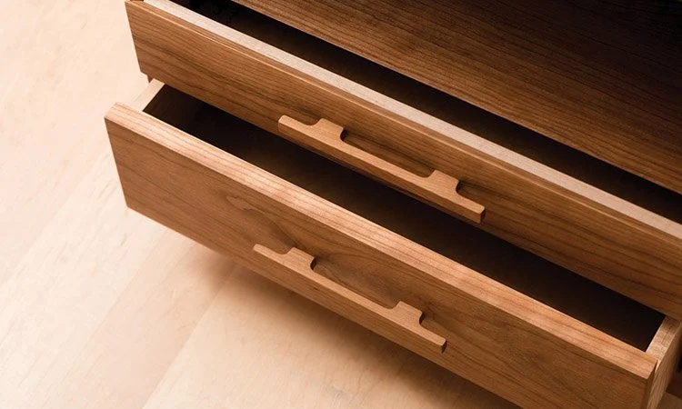 Close-up of an open wooden drawer in a light wood case.