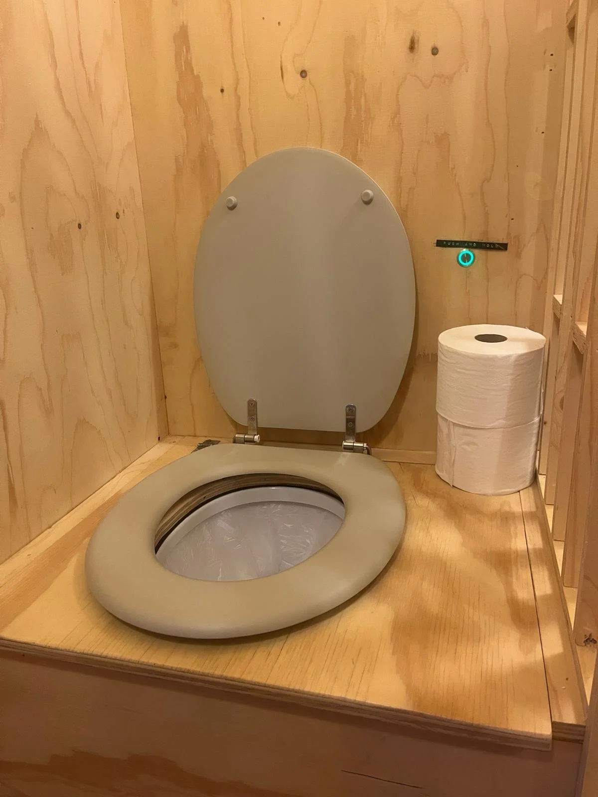 A modern, eco-friendly bathroom with a smart toilet, wooden walls, and a roll of toilet paper on a stand.