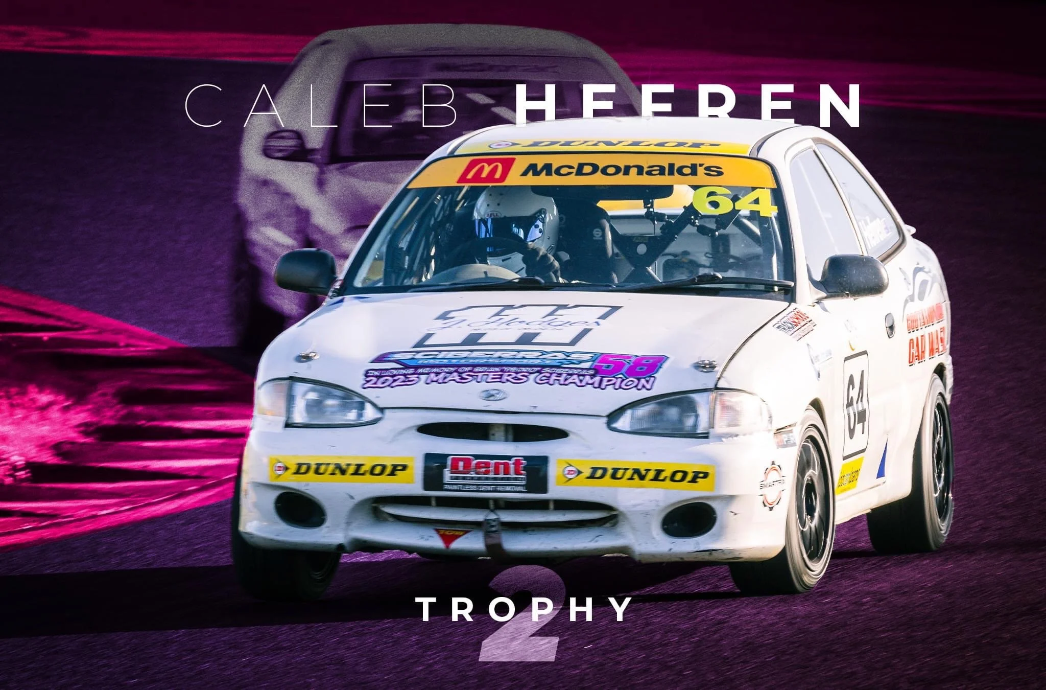 White race car with number 64 on the side, sponsored by McDonald's, Dunlop, and other brands, racing on a track with purple and pink hues, driven by a driver in helmet.