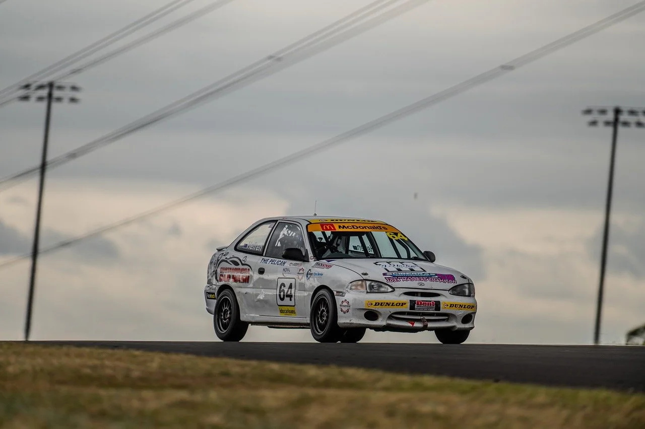 Race car on a track with a cloudy sky background.