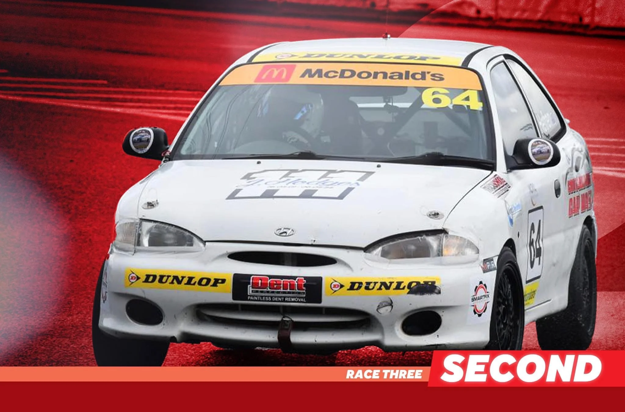 Caleb Hefren's white race car with the number 64 on it, racing on a red track, with sponsor logos including Dunlop and McDonald's, during a race labeled as Race Three, Second place.