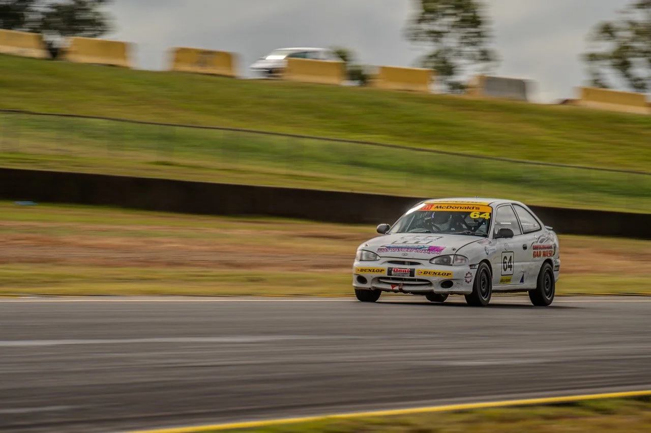 Race car with number 64 on a racetrack during a race.