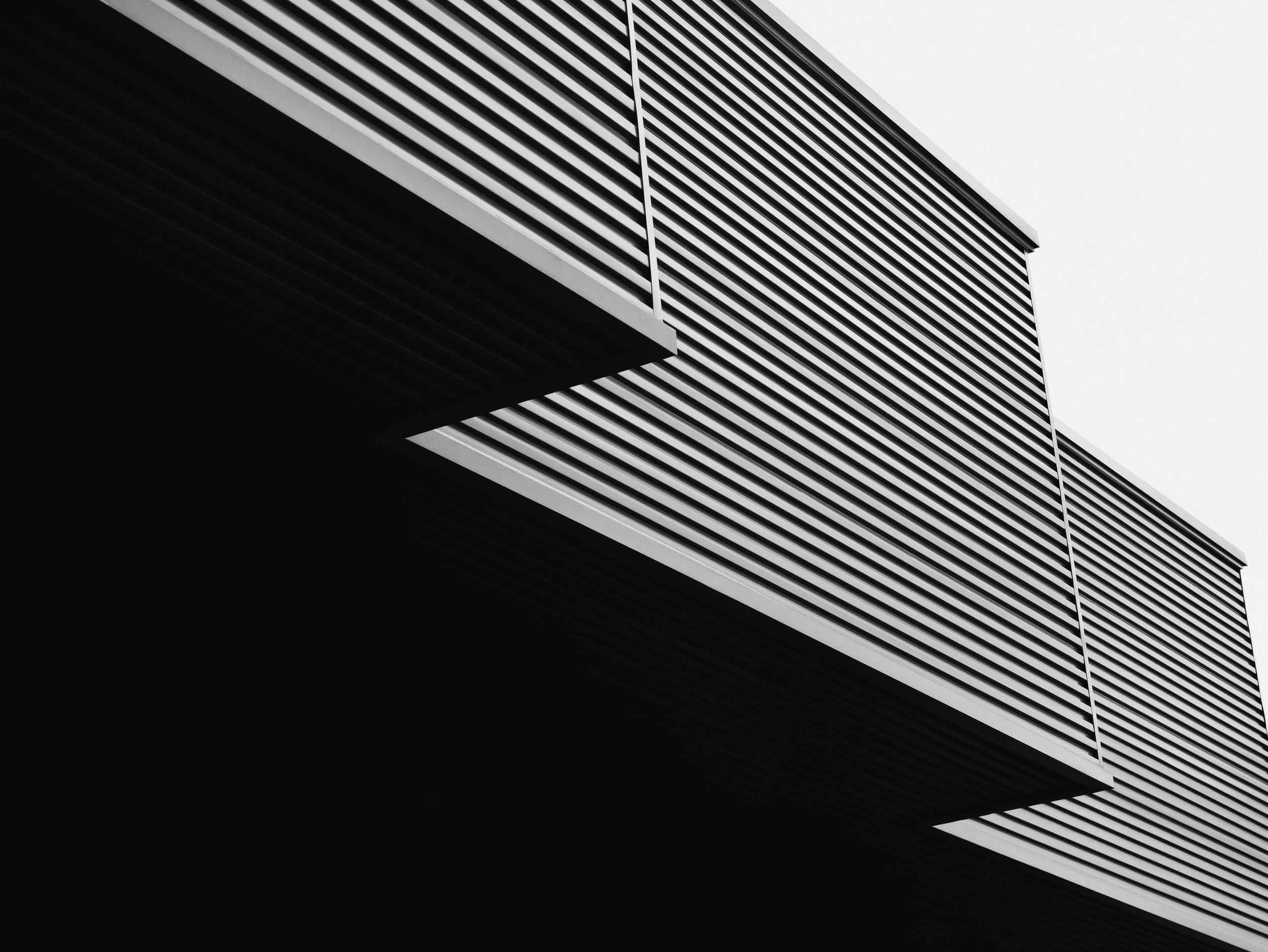 Black and white photo of a modern building with horizontal slatted metal exterior panels and angular overhangs.
