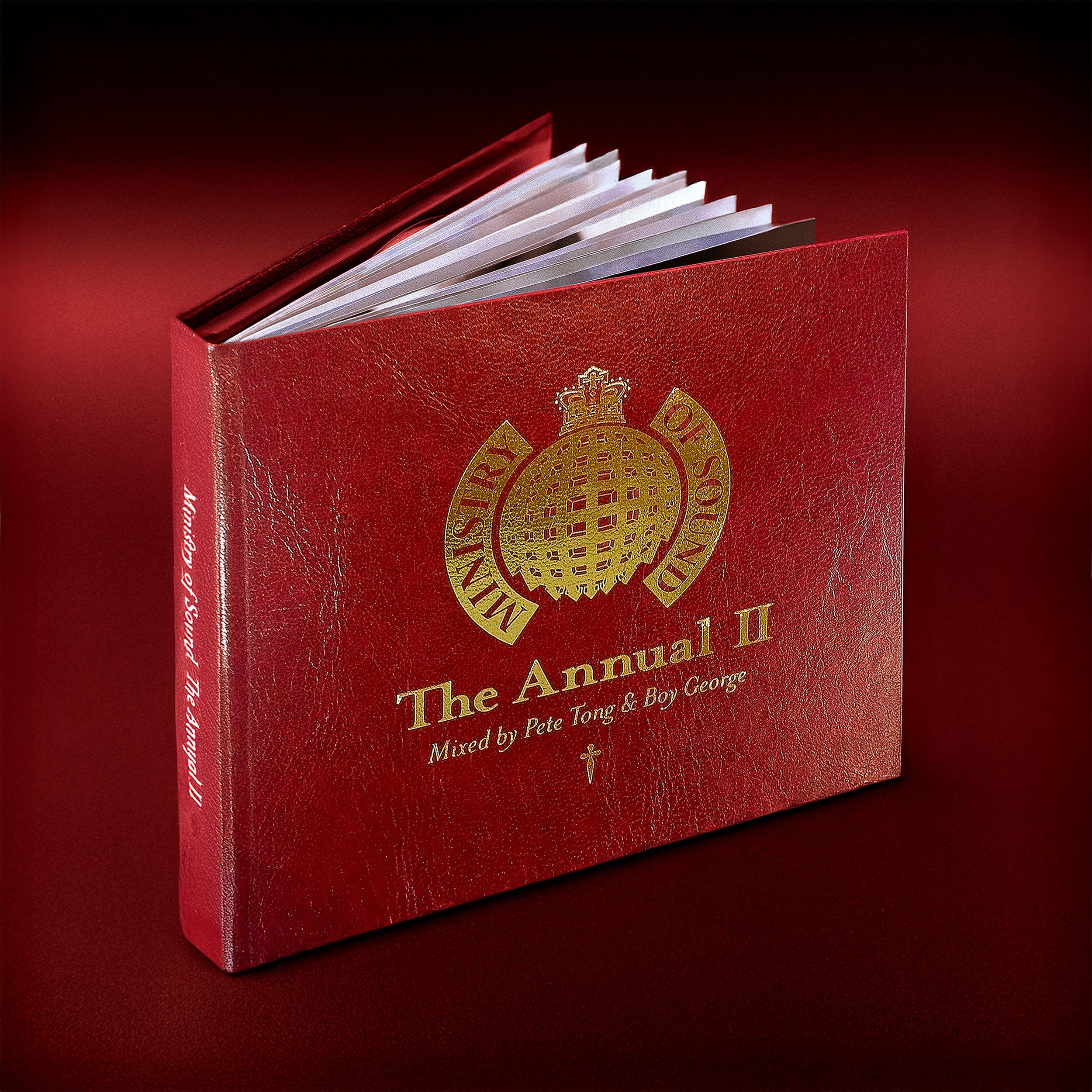 Red album titled 'The Annual II' with gold text and emblem on cover, open to reveal white pages inside, placed on a matching red surface.