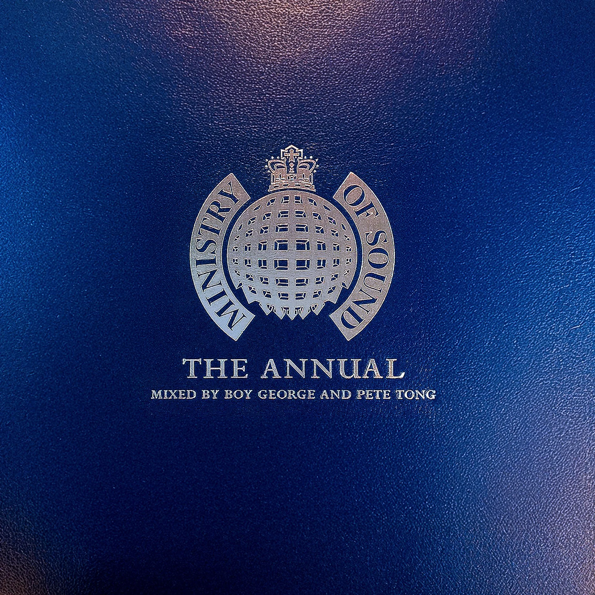Close-up of a blue textured cover with silver text and emblem for 'The Annual', mixed by Boy George and Pete Tong.