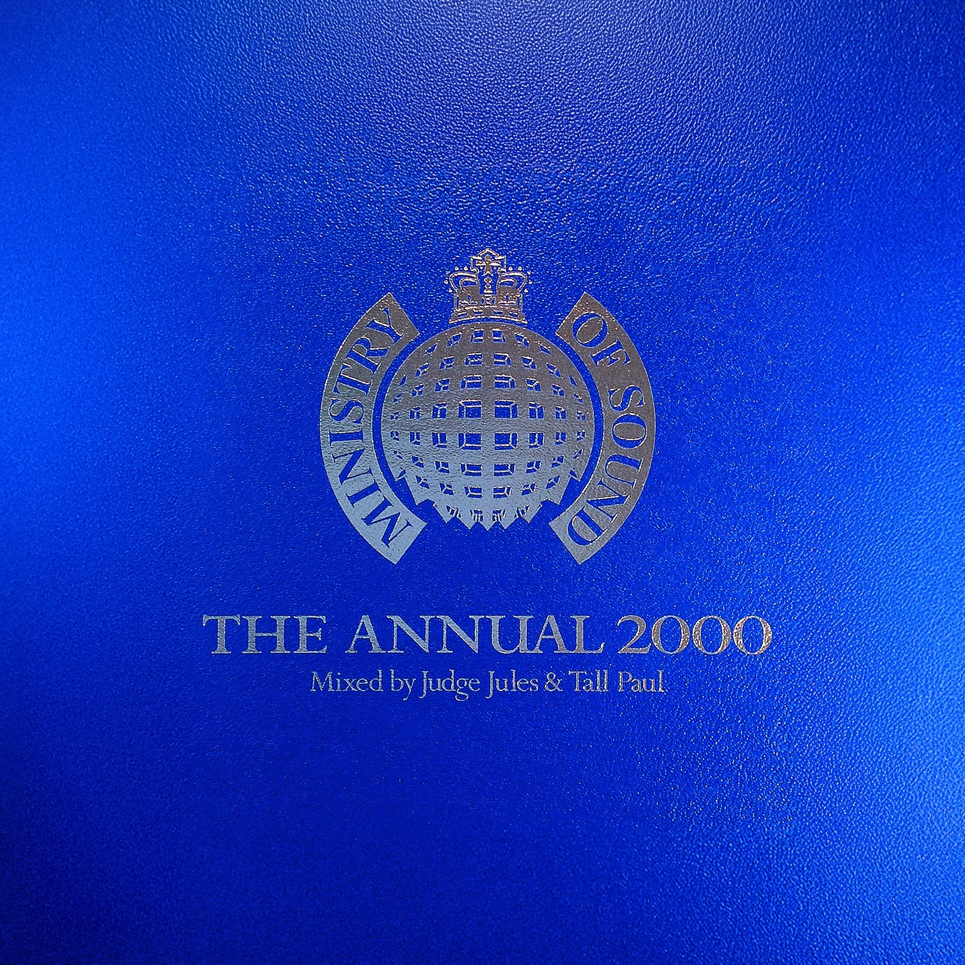 Blue album cover with silver emblem of a globe surrounded by a crown and banner reading 'Ministry of Sound'. Text below states 'The Annual 2000' and 'Mixed by Judge Jules & Tall Paul'.