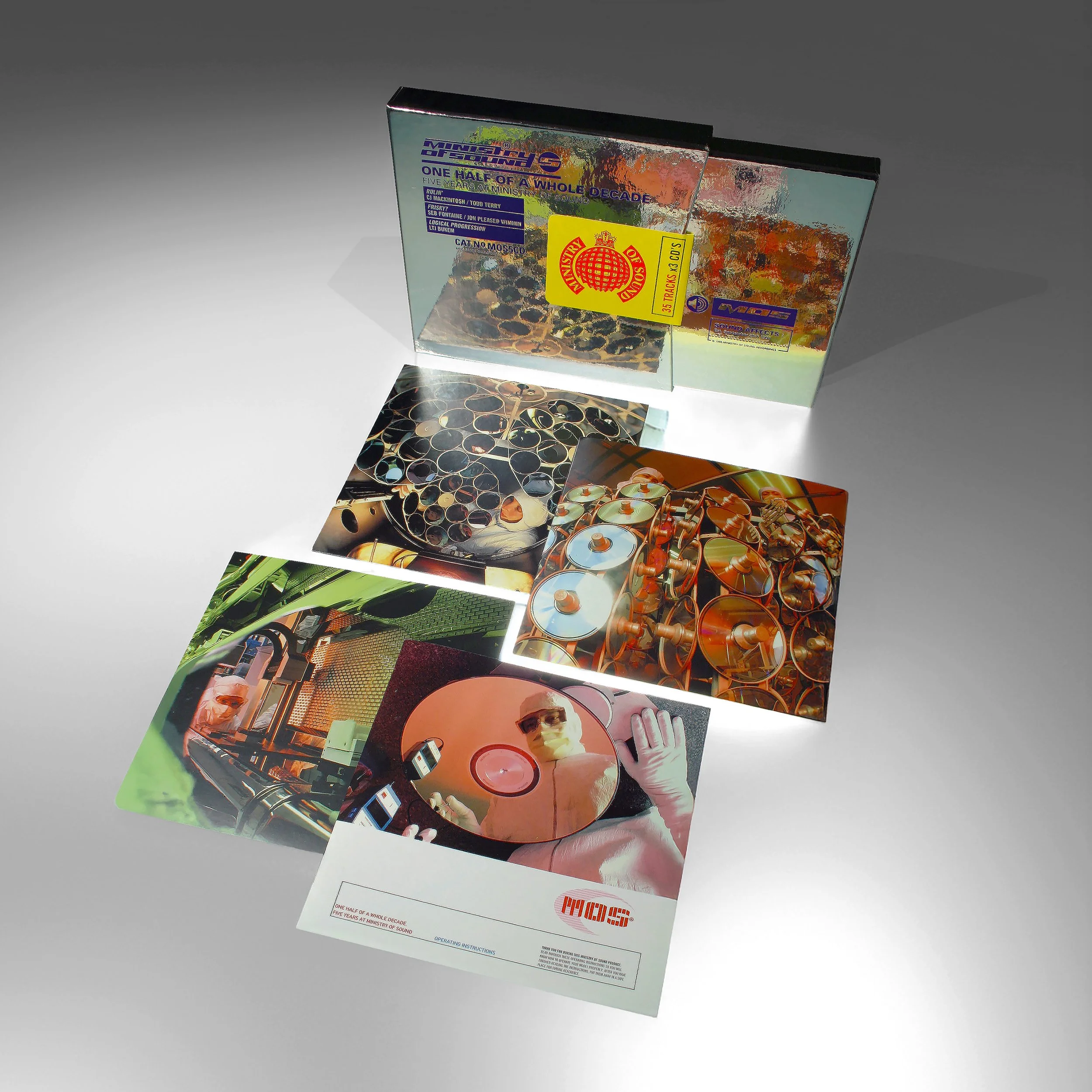 A CD box set with reflective packaging and several CDs, including one featuring a person in sunglasses holding a CD, and artistic images of industrial objects and machinery.