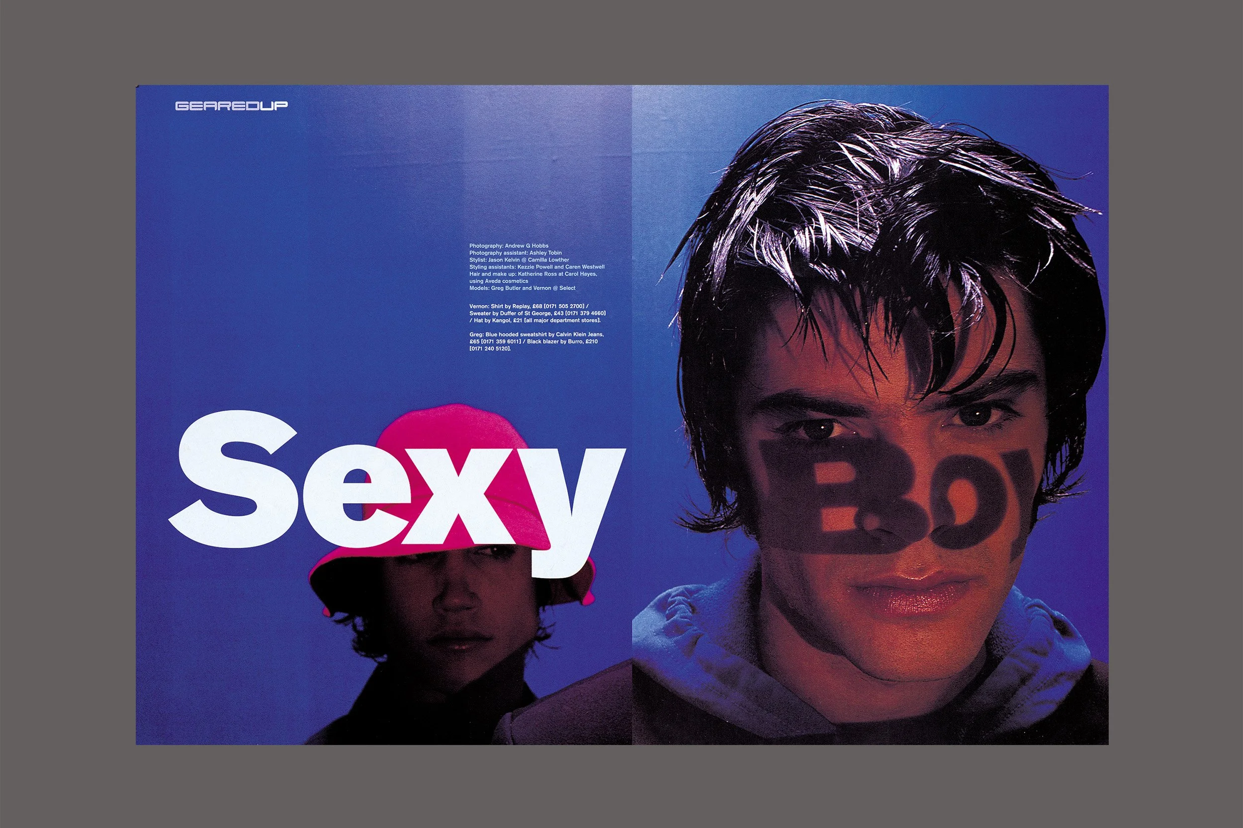 Fashion magazine spread featuring two young men with dark hair on a blue background. The word 'sexy' is printed across the images, with the 'x' partially overlaying the face of the person on the left, who is wearing a pink hat, and the word 'boy' is printed on the face of the person on the right.