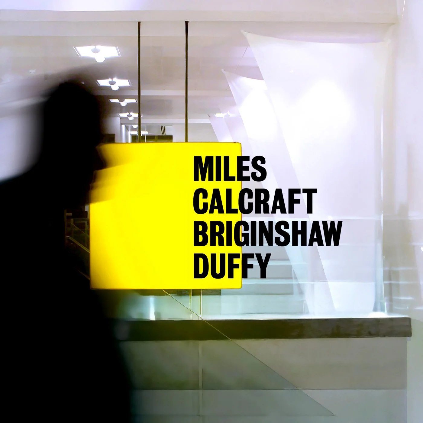 A blurred silhouette of a person walking past a yellow sign with black text that reads 'MILES CALCRAFT BRINGSHAW DUFFY' inside a modern, well-lit building with a white wall and ceiling lights.