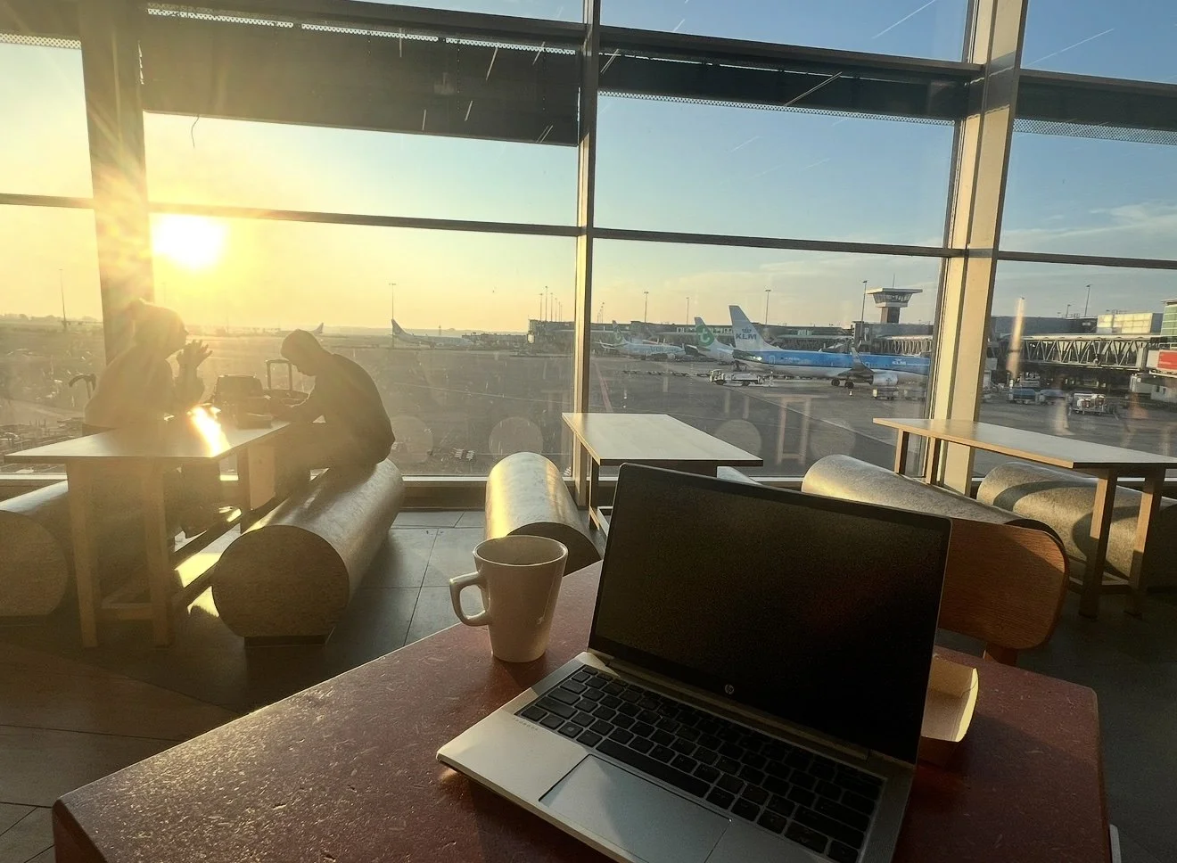 Laptop and coffee cup on a table at schipol airport. Multiple planes int back ground. Business