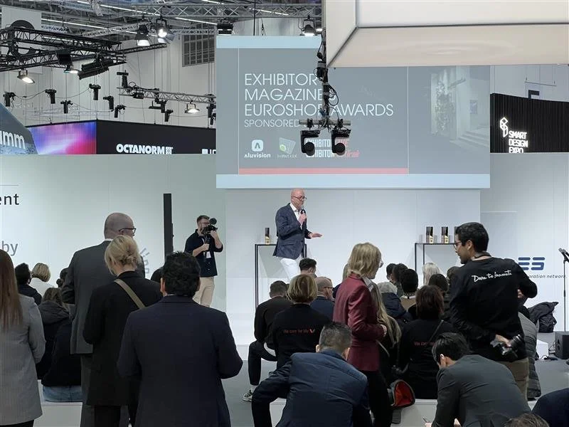 A man on a stage presenting at a EuroShop tradeshow in Germany