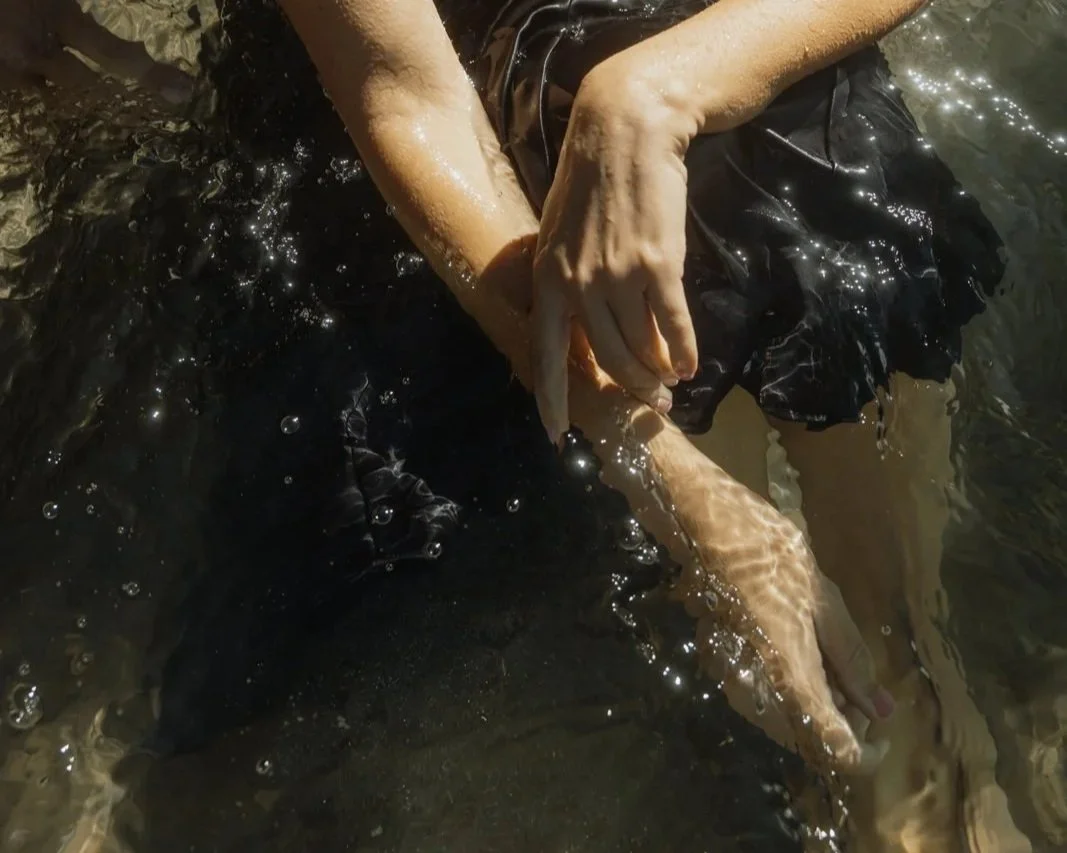 Hände einer Frau, die im Wasser sitzt