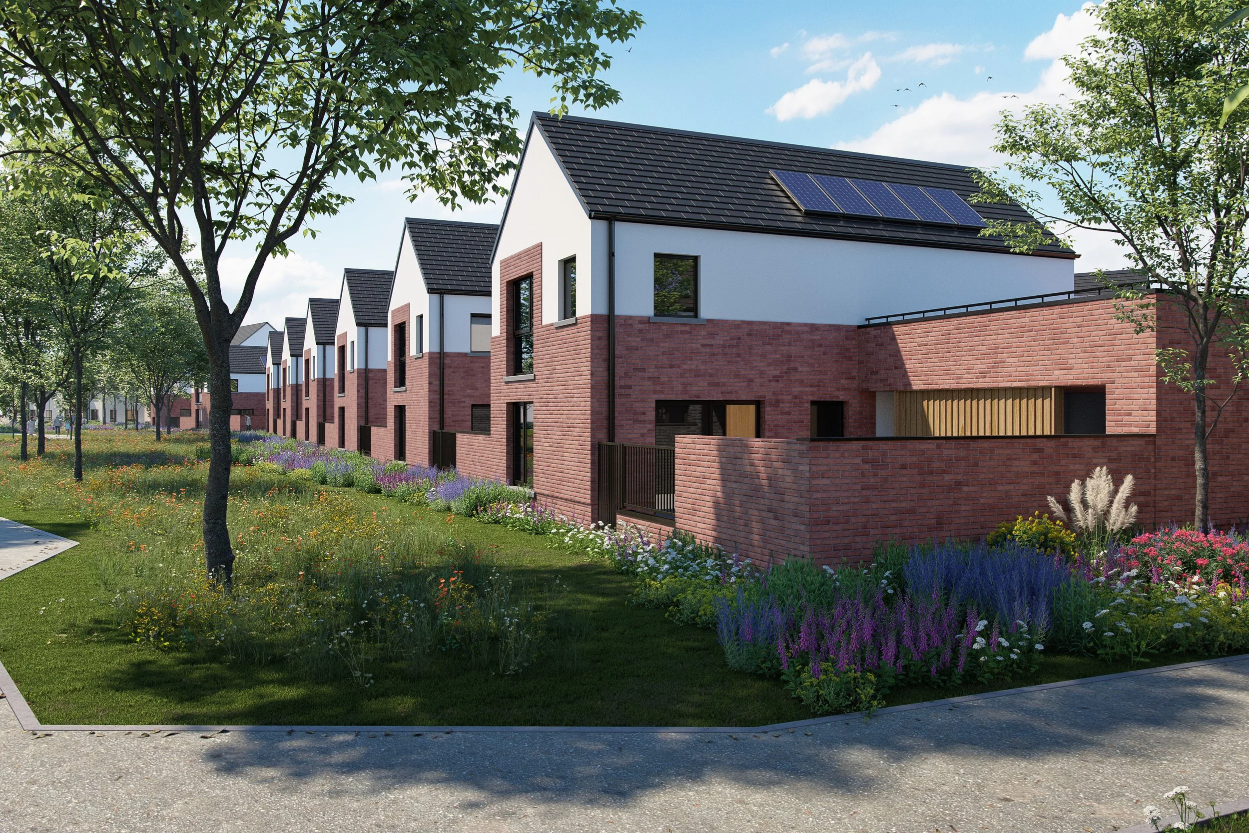 Lines of modern white and brick townhouses with black roofs and solar panels, surrounded by flowering plants and green trees under a blue sky with white clouds.